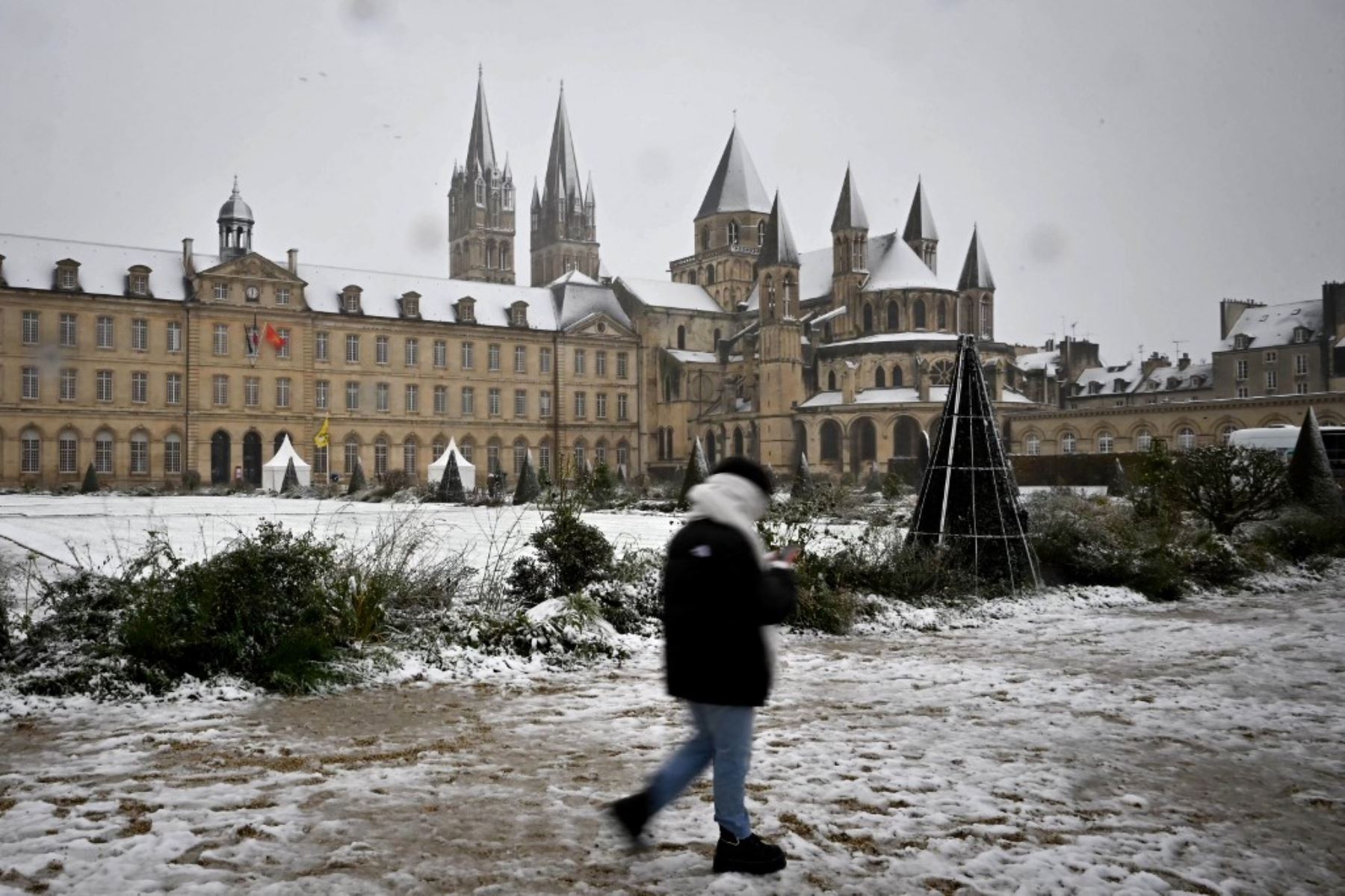 Una mujer camina por el terreno cubierto de nieve, cerca del Ayuntamiento de Caen, noroeste de Francia. Foto: AFP