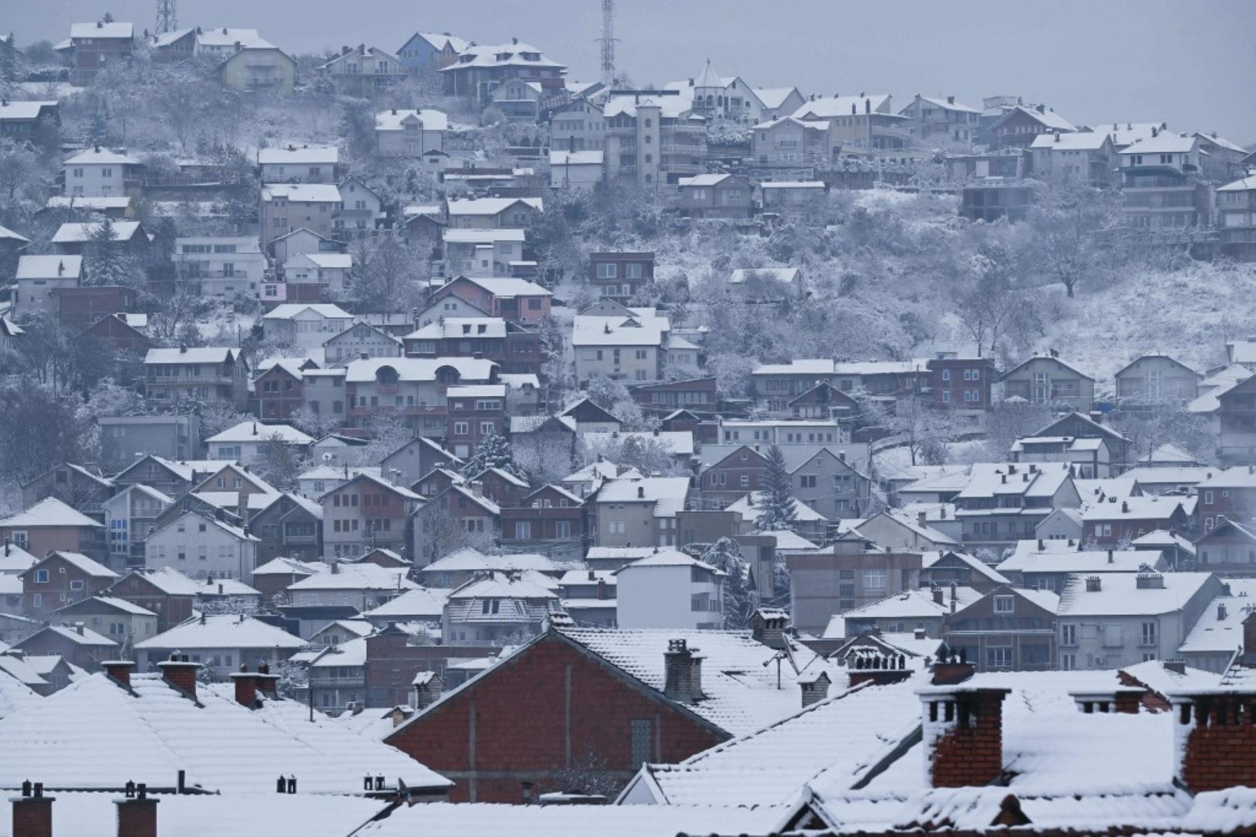 Los tejados de las casas cubiertos de nieve se muestran en las afueras de Pristina, mientras la primera nevada cubre la ciudad. Foto: AFP