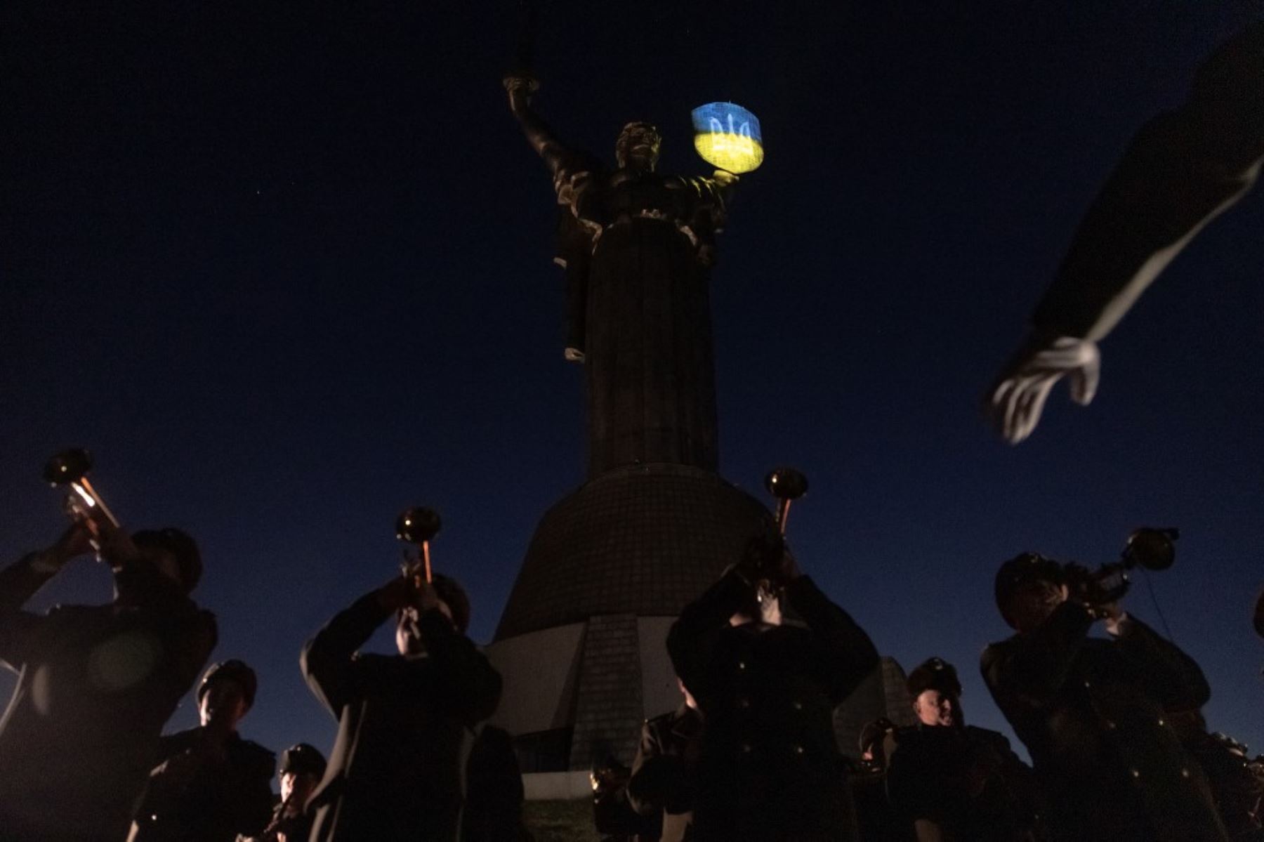 Un músico militar ucraniano actúa ante el Monumento a la Madre Patria blandiendo un escudo de armas ucraniano iluminado durante una ceremonia conmemorativa del día 1.000 de la invasión rusa a Ucrania, en el Museo Nacional de Historia de Ucrania, el 19 de noviembre de 2024. Foto: AFP