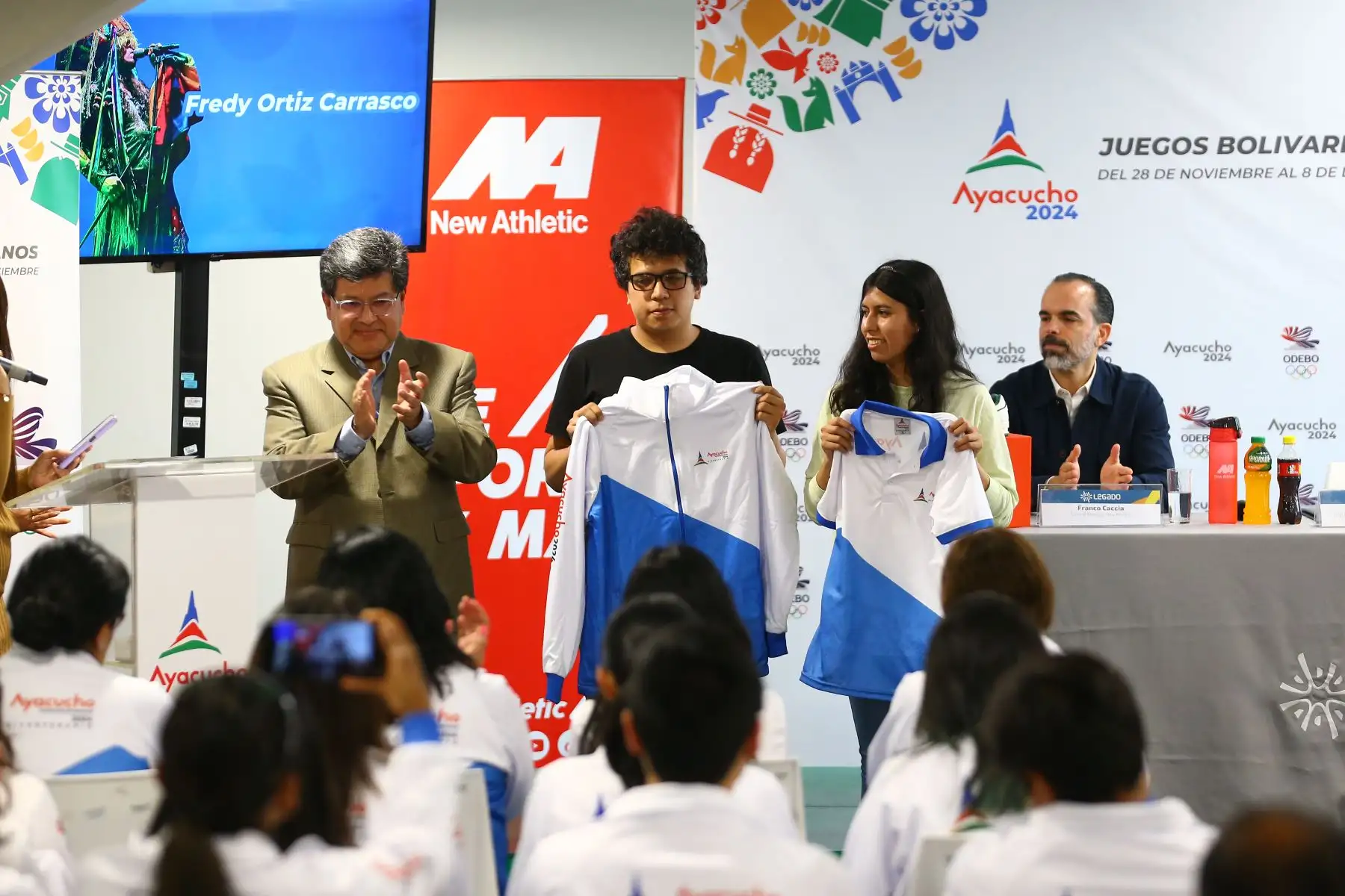 A 2 días de la inauguración de los Juegos Bolivarianos del Bicentenario 2024, los voluntarios reciben indumentaria oficial del certamen deportivo. En la imagen, Franco Caccia, General Manager New Athletic; Enrique Fernández, Director Ejecutivo del Proyecto Especial Legado y Erika Córdova, Gerente de Marketing de AJE Perú. 
Foto: ANDINA/Eddy Ramos