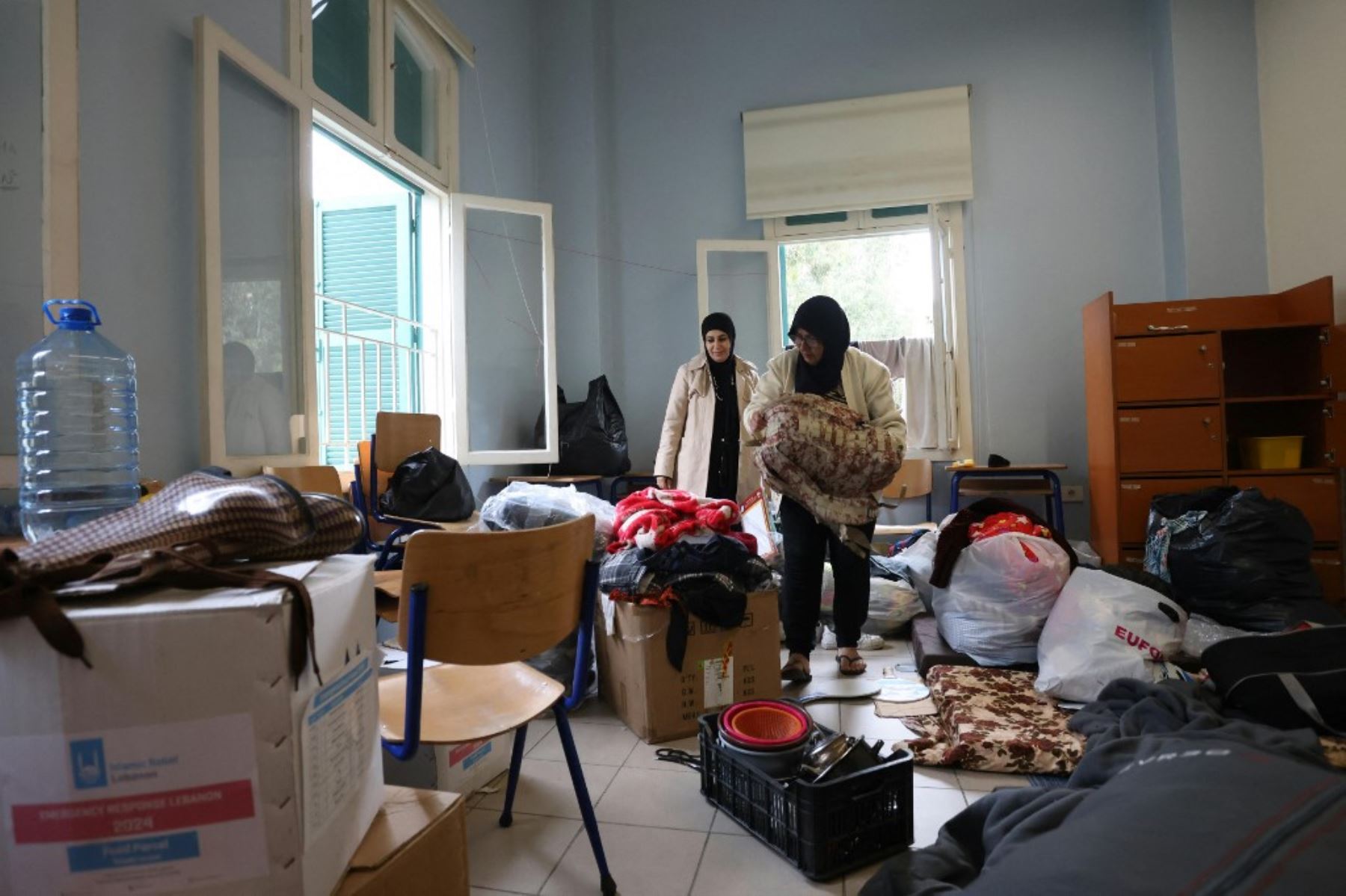 Personas desplazadas empacan sus pertenencias en una escuela convertida en refugio en Beirut el 27 de noviembre de 2024, mientras la gente regresa a sus hogares después de que entrara en vigor un alto el fuego entre Israel y Hezbolá. Se estableció un alto el fuego entre Israel y Hezbollah en el Líbano después de más de un año de combates que han matado a miles de personas. Foto: AFP