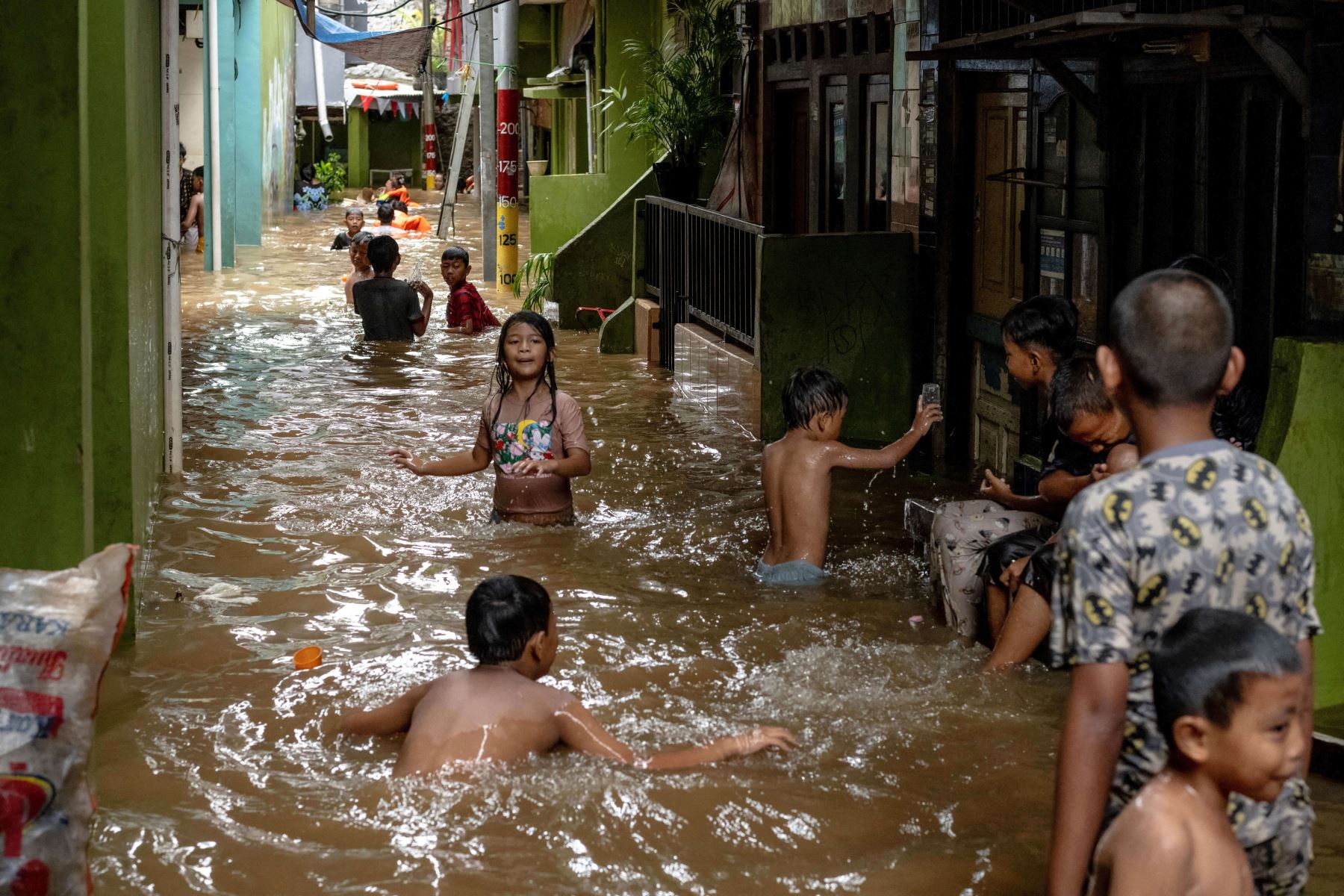 Los niños juegan en las aguas de la inundación resultante del desbordamiento de un río después de fuertes lluvias en Yakarta. AFP