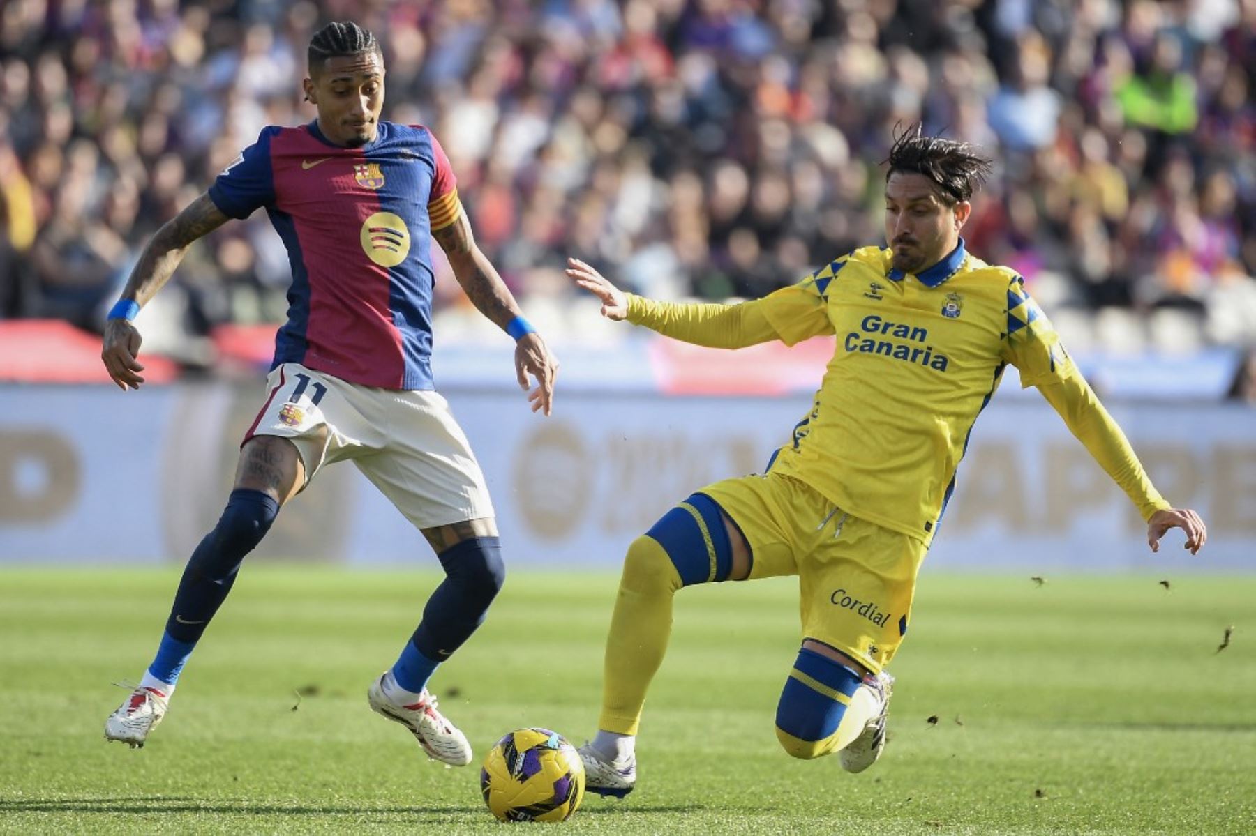 El delantero brasileño del Barcelona #11, Raphinha (Iza), es desafiado por el centrocampista español de Las Palmas #08 Jose Campana durante el partido de fútbol de la liga española entre el FC Barcelona y la UD Las Palmas en la Estadi Olimpic Lluis Companys en Barcelona el 30 de noviembre de 2024. Foto: AFP