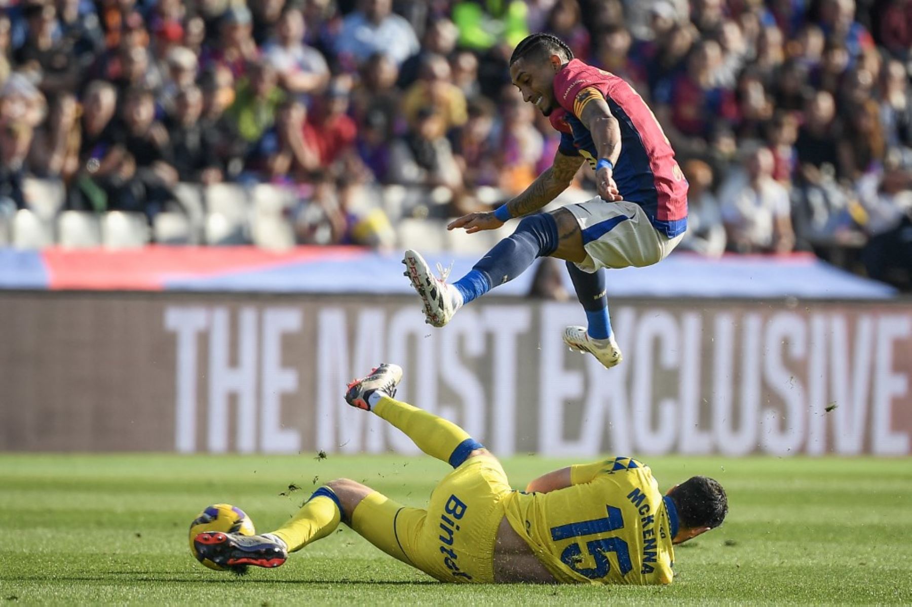 El delantero brasileño del Barcelona #11 Raphinha (arriba) salta sobre el defensa escocés #15 de Las Palmas, Scott McKenna, durante el partido de fútbol de la liga española entre el FC Barcelona y la UD Las Palmas en el Estadi Olimpic Lluis Companys de Barcelona el 30 de noviembre de 2024. Foto: AFP