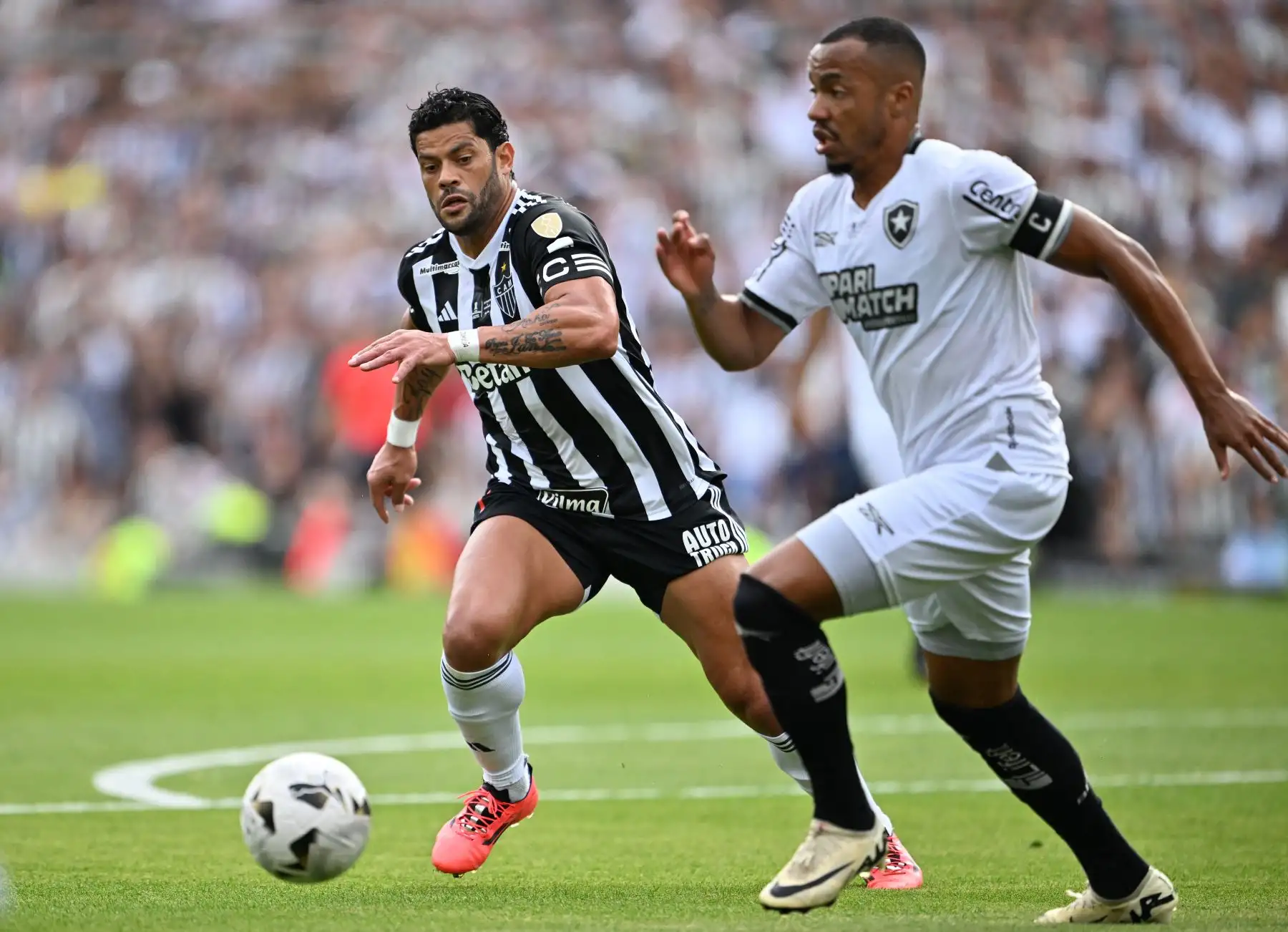 El delantero del Atlético Mineiro Hulk y el mediocampista del Botafogo  Marlon Freitas luchan por el balón durante el partido final de la Copa Libertadores entre los equipos brasileños Atlético Mineiro y Botafogo en el Estadio Mas Monumental de Buenos Aires. Foto: ANDINA/AFP