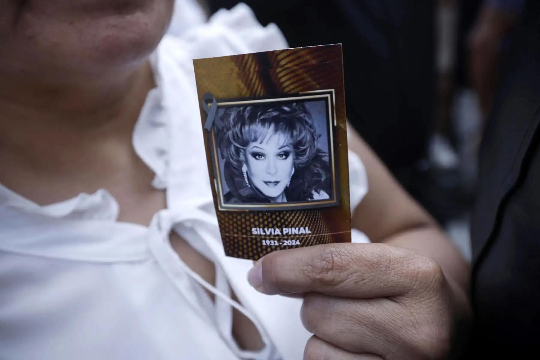Una mujer muestra una calcomanía con la imagen de la actriz mexicana Silvia Pinal afuera del Palacio de Bellas Artes durante su funeral en la Ciudad de México el 30 de noviembre de 2024. Pinal, considerada la última diva del cine mexicano. Foto: ANDINA/AFP