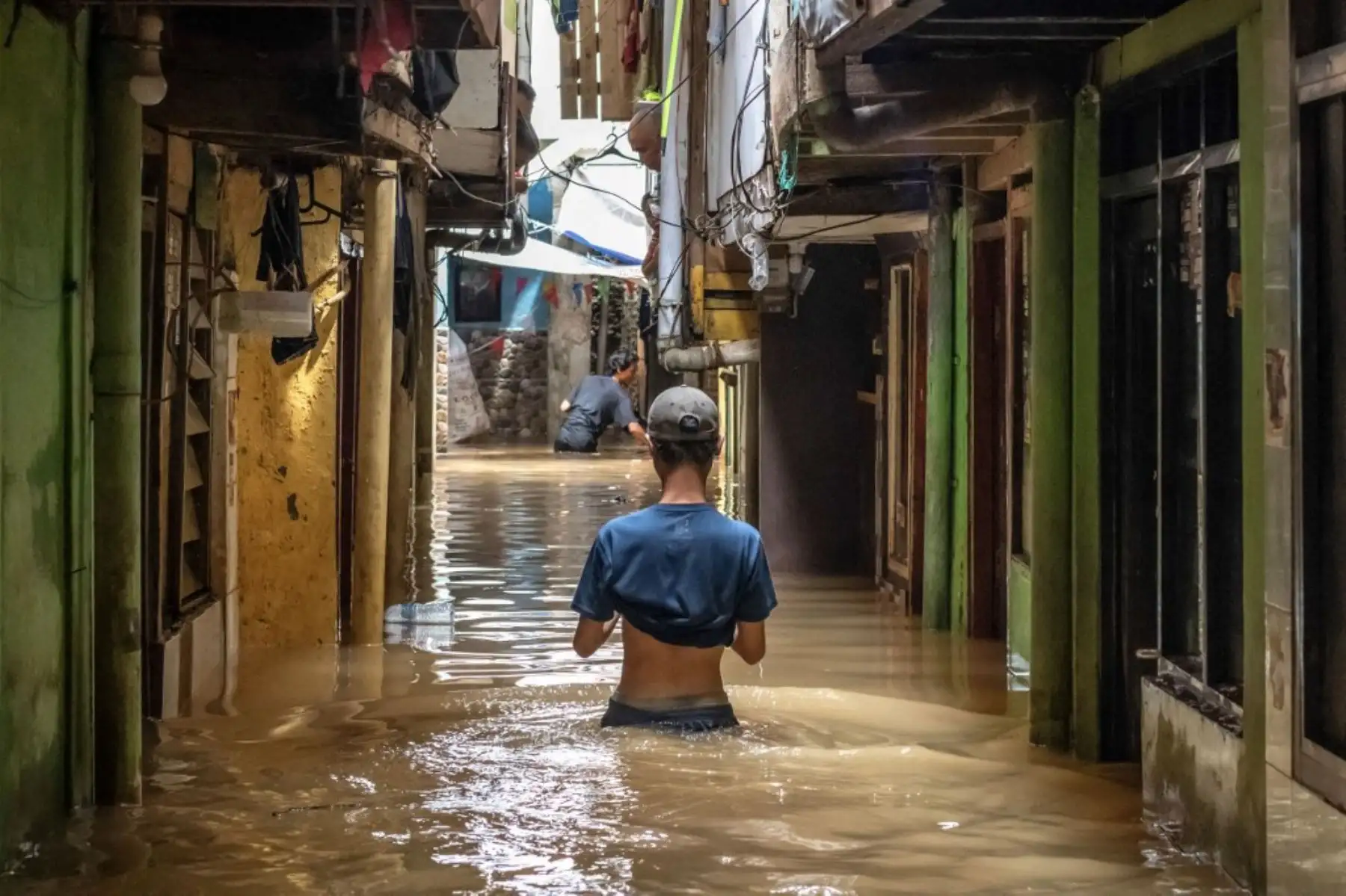 Un hombre vadea a través de las inundaciones resultantes del desbordamiento de un río después de una fuerte lluvia en Yakarta el 28 de noviembre de 2024. (Foto de BAY ISMOYO / AFP)