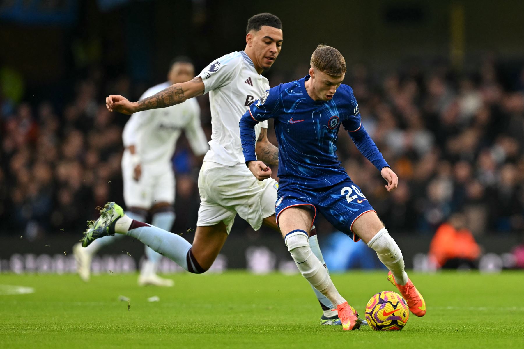 El centrocampista inglés del Chelsea #20, Cole Palmer, compite por el balón con el centrocampista inglés #27 del Aston Villa, Morgan Rogers, durante el partido de fútbol de la Premier League inglesa entre Chelsea y Aston Villa en Stamford Bridge en Londres el 1 de diciembre de 2024. (Foto de Glyn KIRK / AFP)