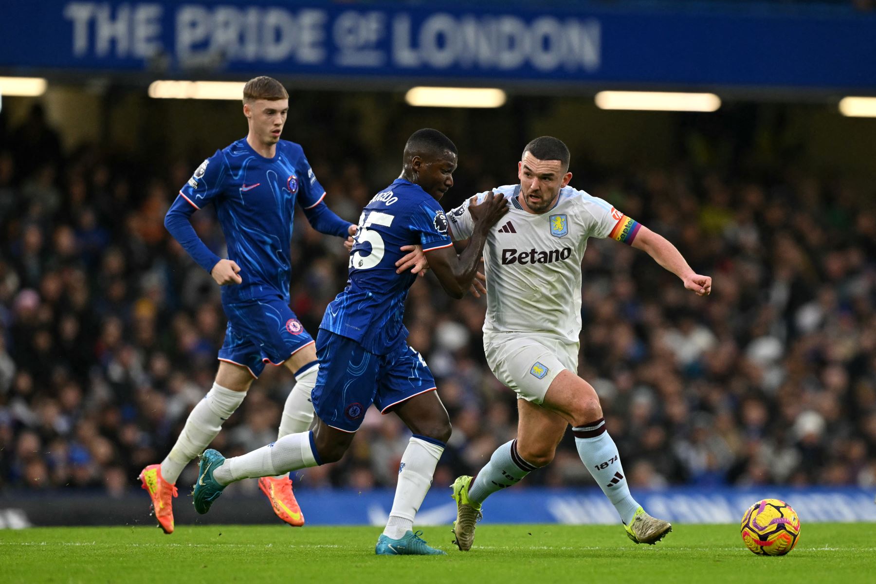 El centrocampista ecuatoriano del Chelsea #25 Moises Caicedo (C) compite por el balón con el centrocampista escocés del Aston Villa #07 John McGinn durante el partido de fútbol de la Premier League inglesa entre Chelsea y Aston Villa en Stamford Bridge en Londres el 1 de diciembre de 2024. (Foto de Glyn KIRK / AFP)