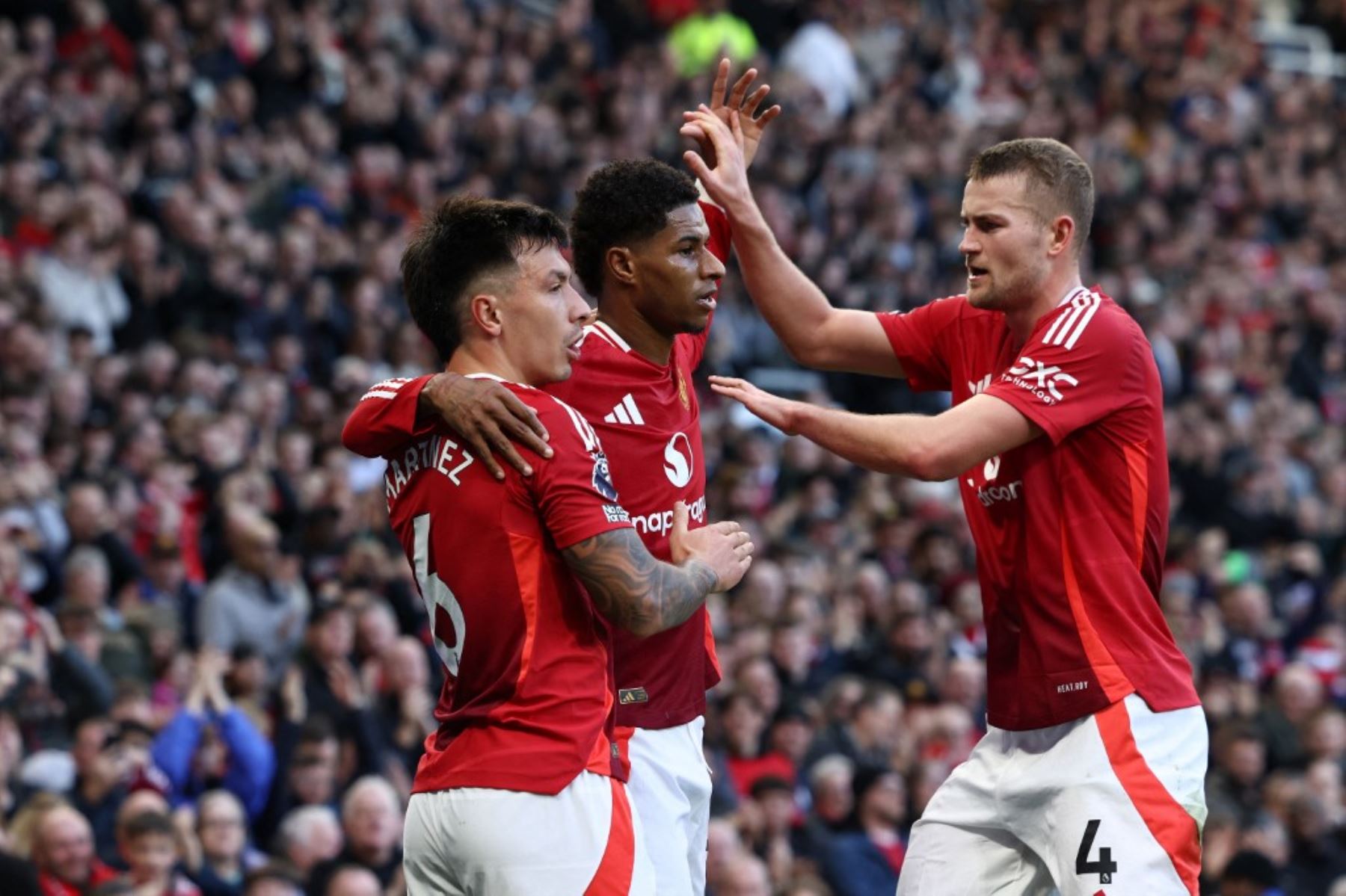 El delantero inglés #10 del Manchester United, Marcus Rashford (C), celebra con el defensor argentino #06 del Manchester United, Lisandro Martínez (izquierda) y el defensor holandés #04 del Manchester United, Matthijs de Ligt (R), después de marcar el gol inaugural del partido de fútbol de la Premier League inglesa entre el Manchester United y el Everton en Old Trafford en Manchester, noroeste de Inglaterra, el 1 de diciembre de 2024. (Foto de Darren Staples / AFP)