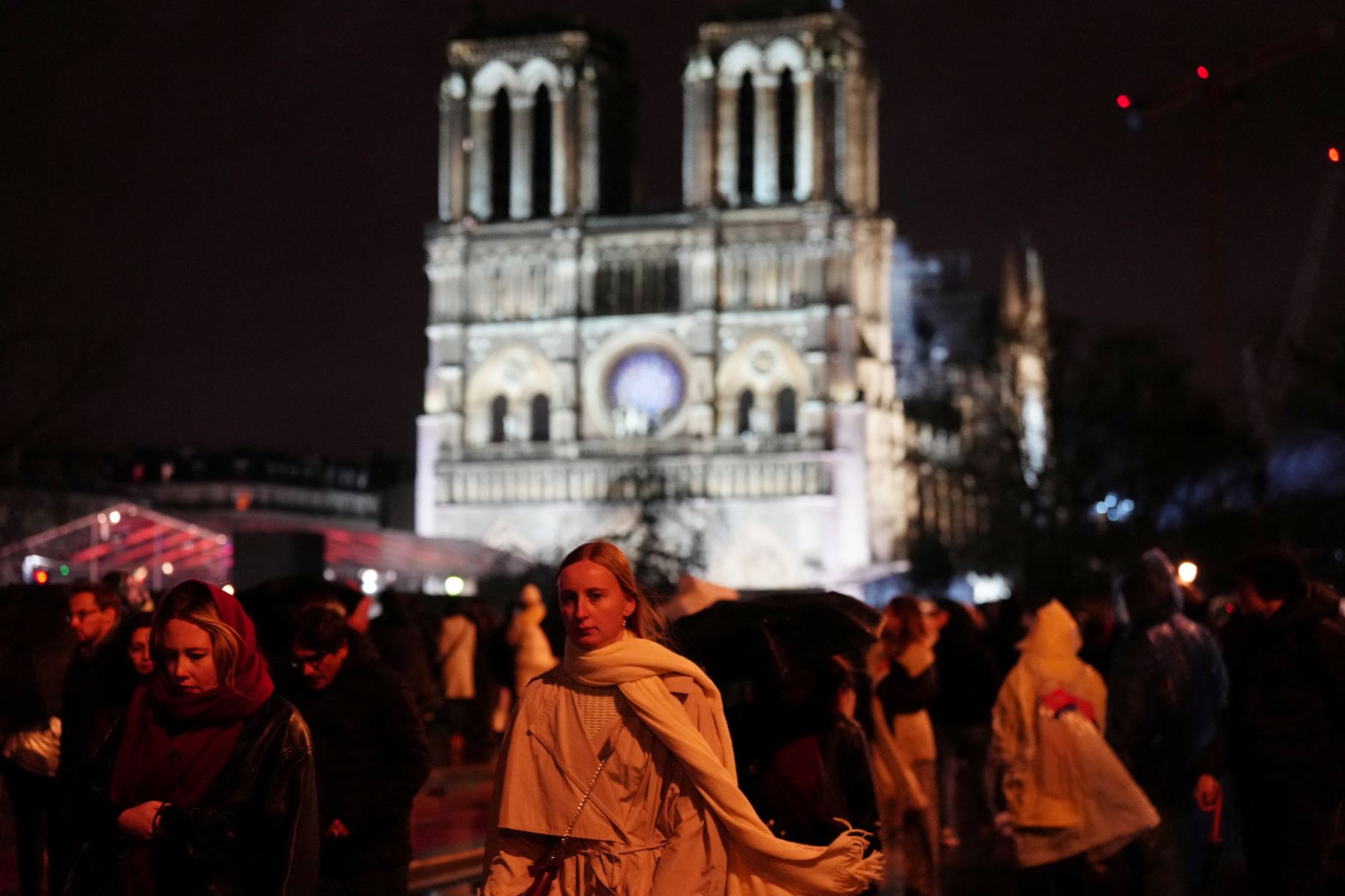 Una mujer camina afuera de la Catedral de Notre-Dame mientras está iluminada durante una ceremonia para marcar la reapertura de la histórica Catedral.AFP