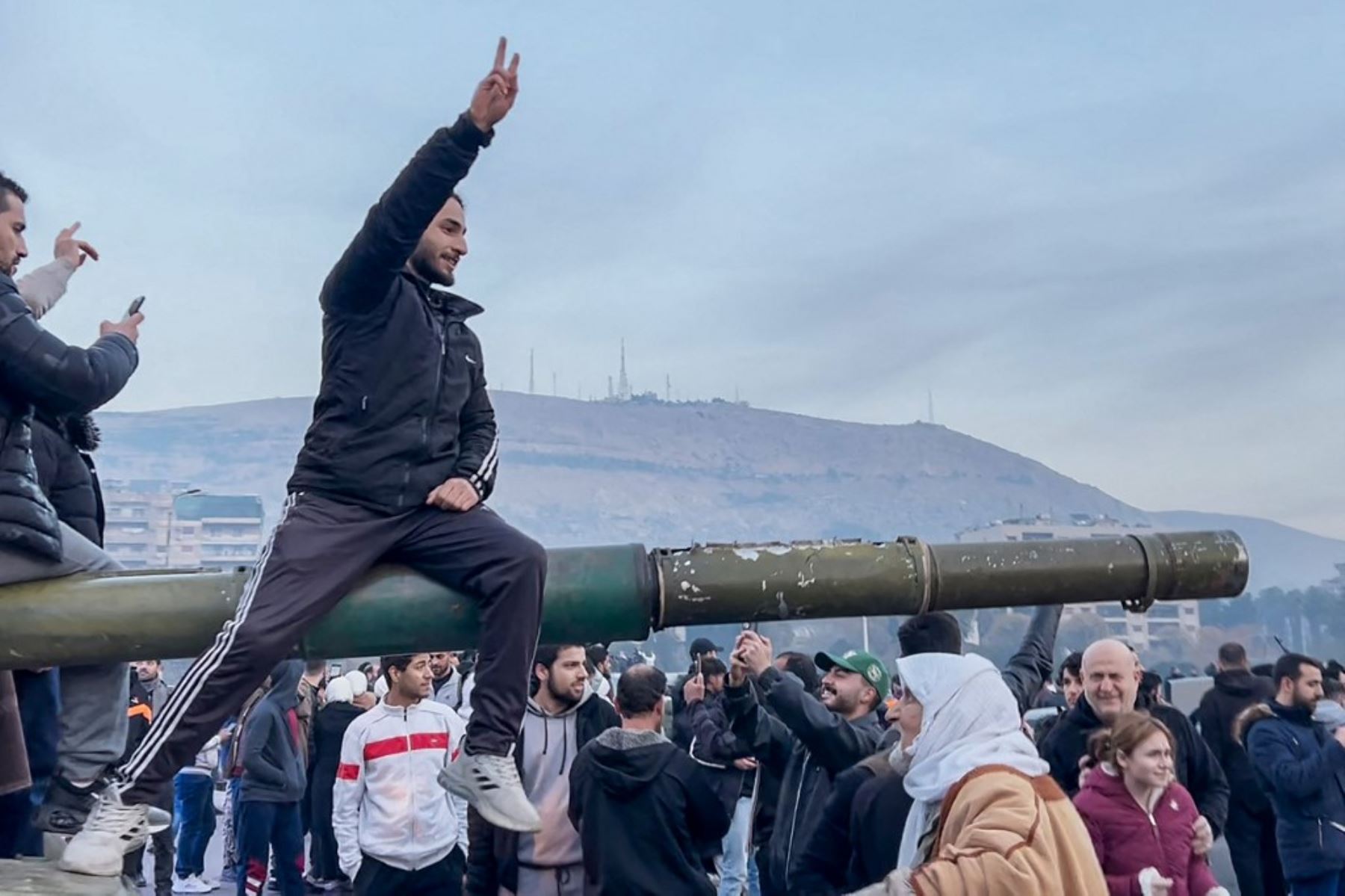 Esta captura de pantalla tomada de AFPTV muestra a personas sentadas en un tanque mientras se reúnen en la Plaza Umayyad en Damasco el 8 de diciembre de 2024. Los rebeldes liderados por islamistas declararon que habían tomado Damasco en una ofensiva relámpago el 8 de diciembre, enviando al presidente Bashar al-Assad huyendo y poniendo fin a cinco décadas de gobierno de Baath en Siria. (Foto de AFPTV / AFP)