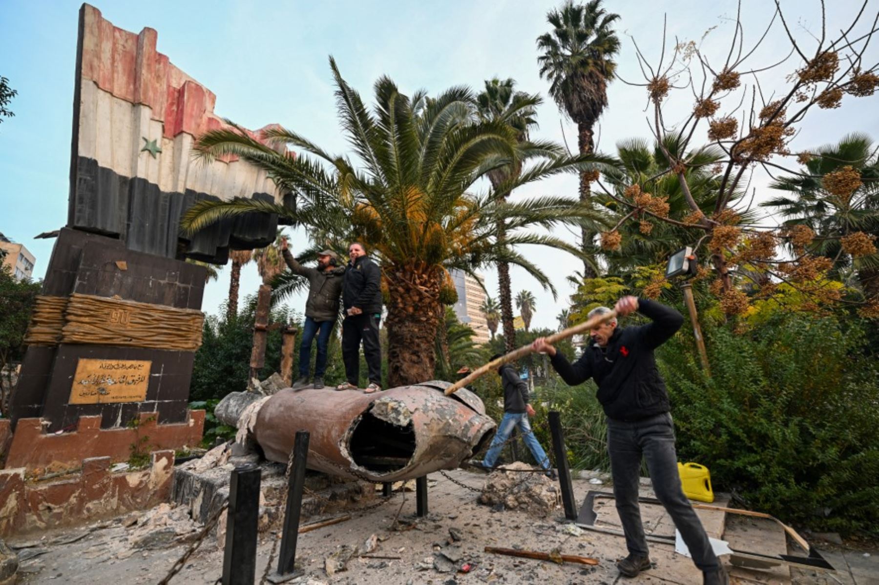 La gente se para en lo alto de una estatua derrocada del difunto presidente de Siria, Hafez al-Assad, en Damasco el 8 de diciembre de 2024. Los rebeldes liderados por islamistas declararon que habían tomado Damasco en una ofensiva relámpago el 8 de diciembre, enviando al presidente Bashar al-Assad huyendo y poniendo fin a cinco décadas de gobierno de Baath en Siria. (Foto de LOUAI BESHARA / AFP)