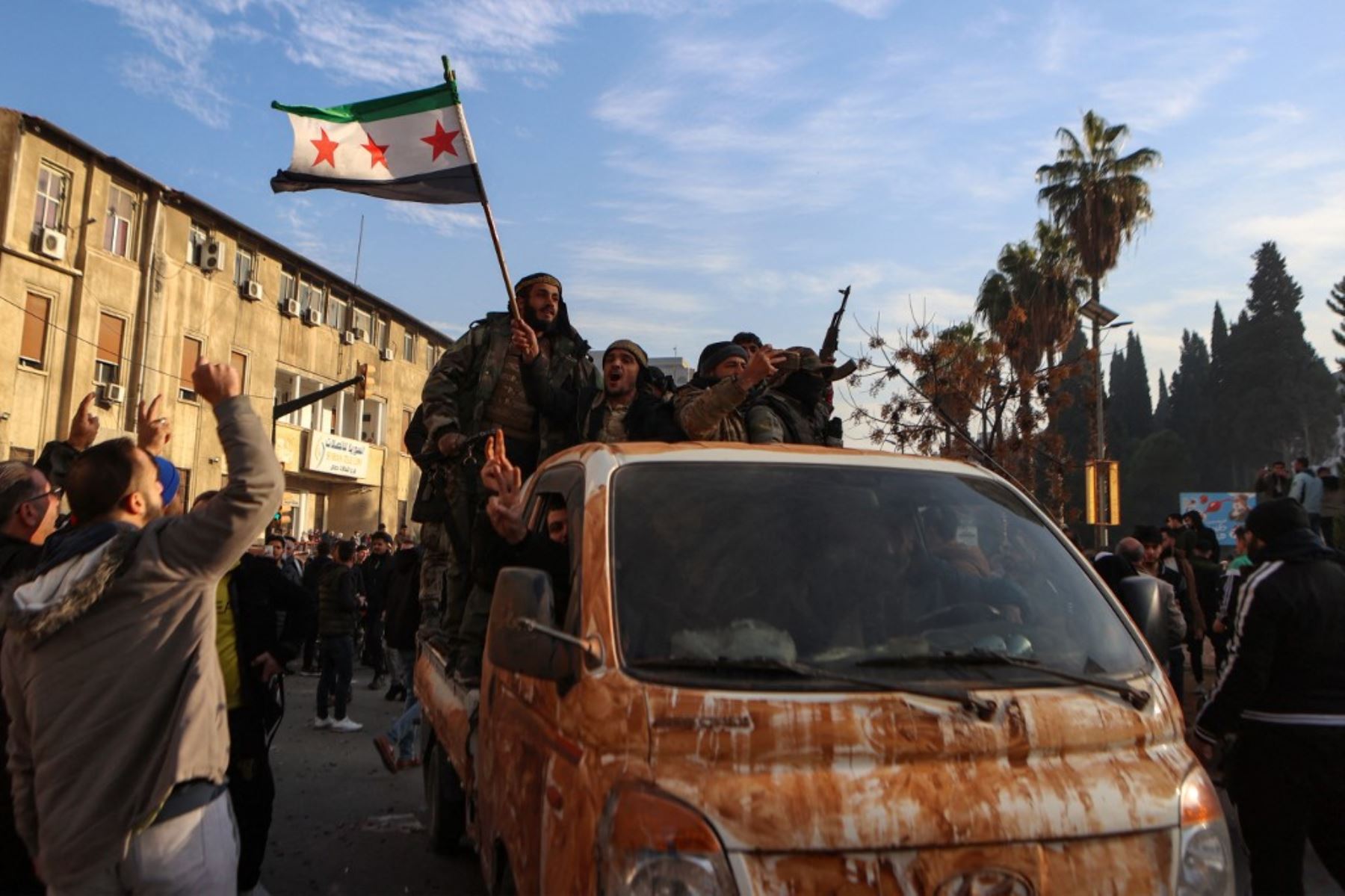 Los combatientes rebeldes sirios celebran cerca de la Torre del Reloj en Homs el 8 de diciembre de 2024, después de que las fuerzas rebeldes entraran en la tercera ciudad de Siria durante la noche. Los rebeldes liderados por islamistas declararon que habían tomado Damasco en una ofensiva relámpago el 8 de diciembre, enviando al presidente Bashar al-Assad huyendo y poniendo fin a cinco décadas de gobierno de Baath en Siria. (Foto de Aaref WATAD / AFP)