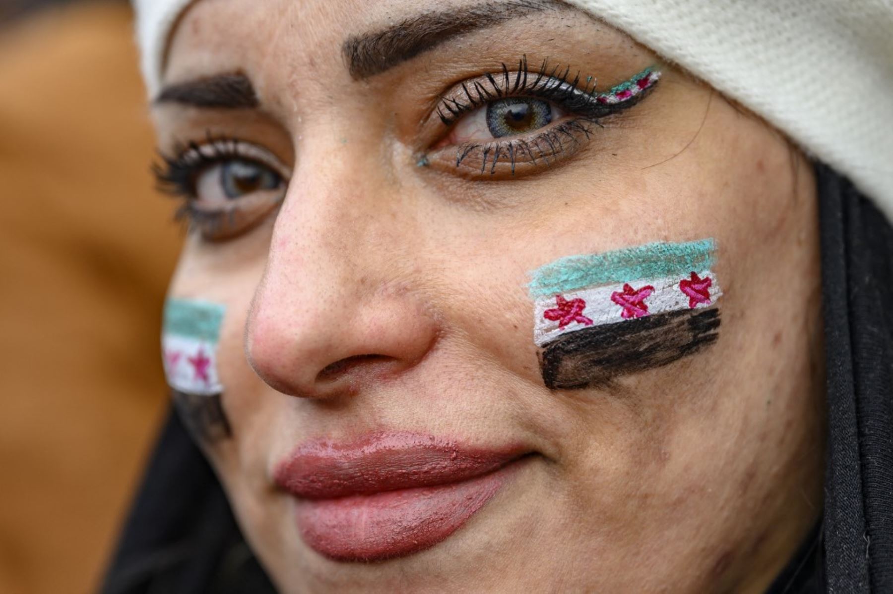 Una mujer con banderas de la oposición siria en sus mejillas observa cómo los residentes sirios en Turquía celebran el fin del gobierno de Baath en Siria después de que los combatientes rebeldes tomaran el control de Damasco durante la noche, en la mezquita Fatih, en Estambul, el 8 de diciembre de 2024. Los rebeldes liderados por islamistas declararon que habían tomado Damasco en una ofensiva relámpago el 8 de diciembre, enviando al presidente Bashar al-Assad huyendo y poniendo fin a cinco décadas de gobier