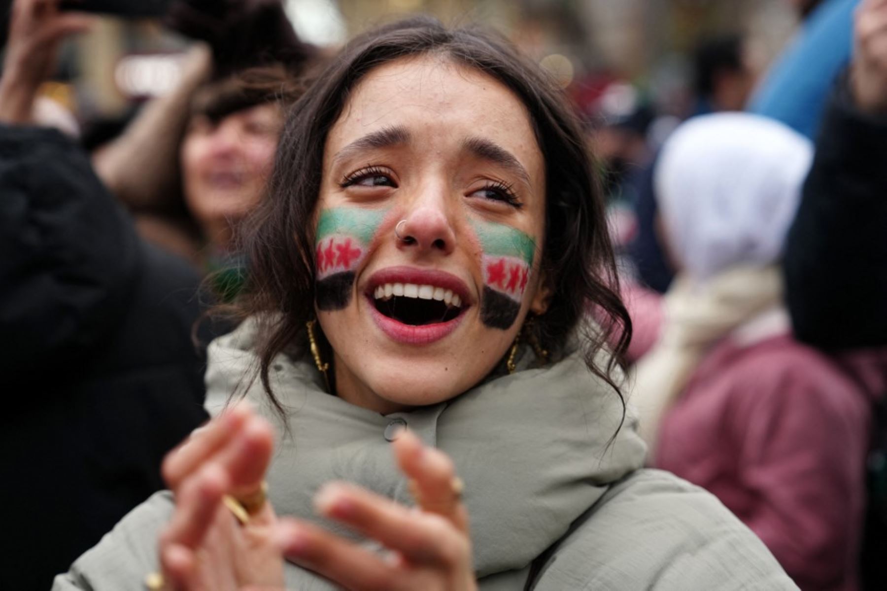 Una mujer, con una bandera de la oposición pintada en su rostro, aplaude mientras miembros de la comunidad siria y simpatizantes se reúnen para celebrar la caída del presidente sirio Bashar al-Assad ante una ofensiva de los rebeldes liderados por islamistas, en París el 8 de diciembre de 2024. Los rebeldes liderados por islamistas derrocaron al gobernante sirio Bashar al-Assad en una ofensiva relámpago que un enviado de la ONU calificó como "un momento decisivo" para la nación marcada por la guerra civil. (Foto de Dimitar DILKOFF / AFP)