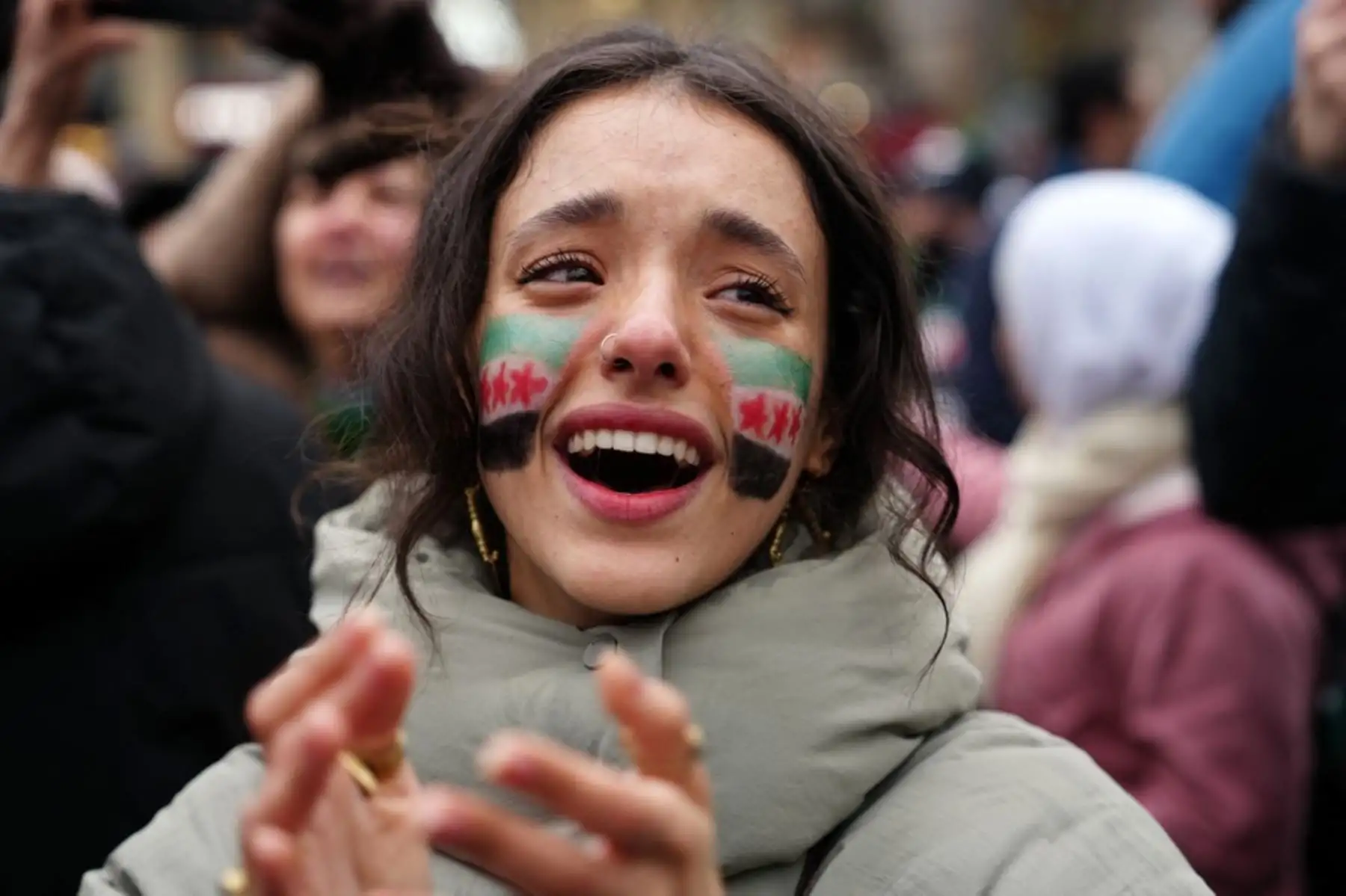 Una mujer, con una bandera de la oposición pintada en su rostro, aplaude mientras miembros de la comunidad siria y simpatizantes se reúnen para celebrar la caída del presidente sirio Bashar al-Assad ante una ofensiva de los rebeldes liderados por islamistas, en París el 8 de diciembre de 2024. Los rebeldes liderados por islamistas derrocaron al gobernante sirio Bashar al-Assad en una ofensiva relámpago que un enviado de la ONU calificó como "un momento decisivo" para la nación marcada por la guerra civil. (Foto de Dimitar DILKOFF / AFP)