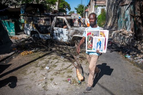 Un hombre sostiene imágenes religiosas en una calle de Poste Marchand, este martes, en Puerto Príncipe, Haití. Foto: ANDINA/EFE