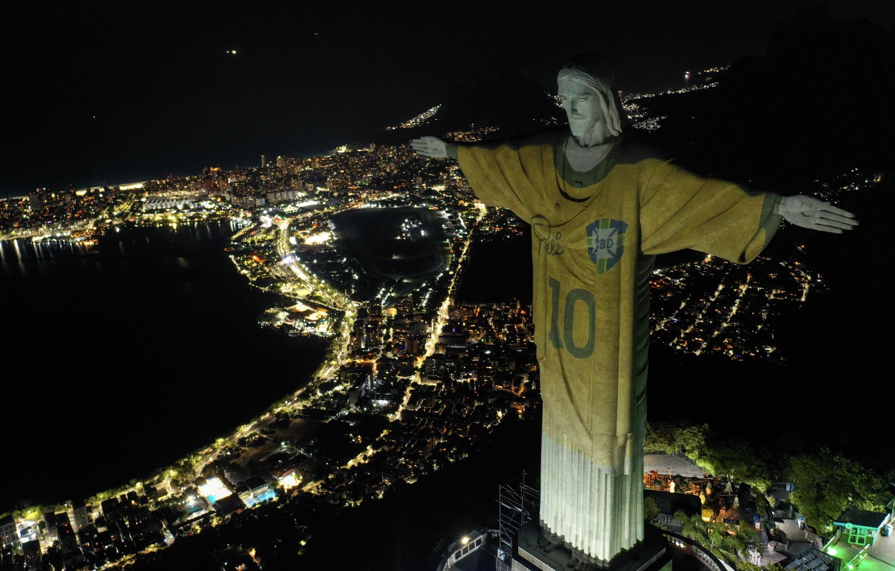 Vista aérea que muestra una imagen proyectada sobre la estatua del Cristo Redentor, que rinde homenaje a la leyenda del fútbol brasileño Pelé en el primer aniversario de su muerte, en el monte Corcovado en Río de Janeiro, Brasil. Foto: ANDINA/AFP