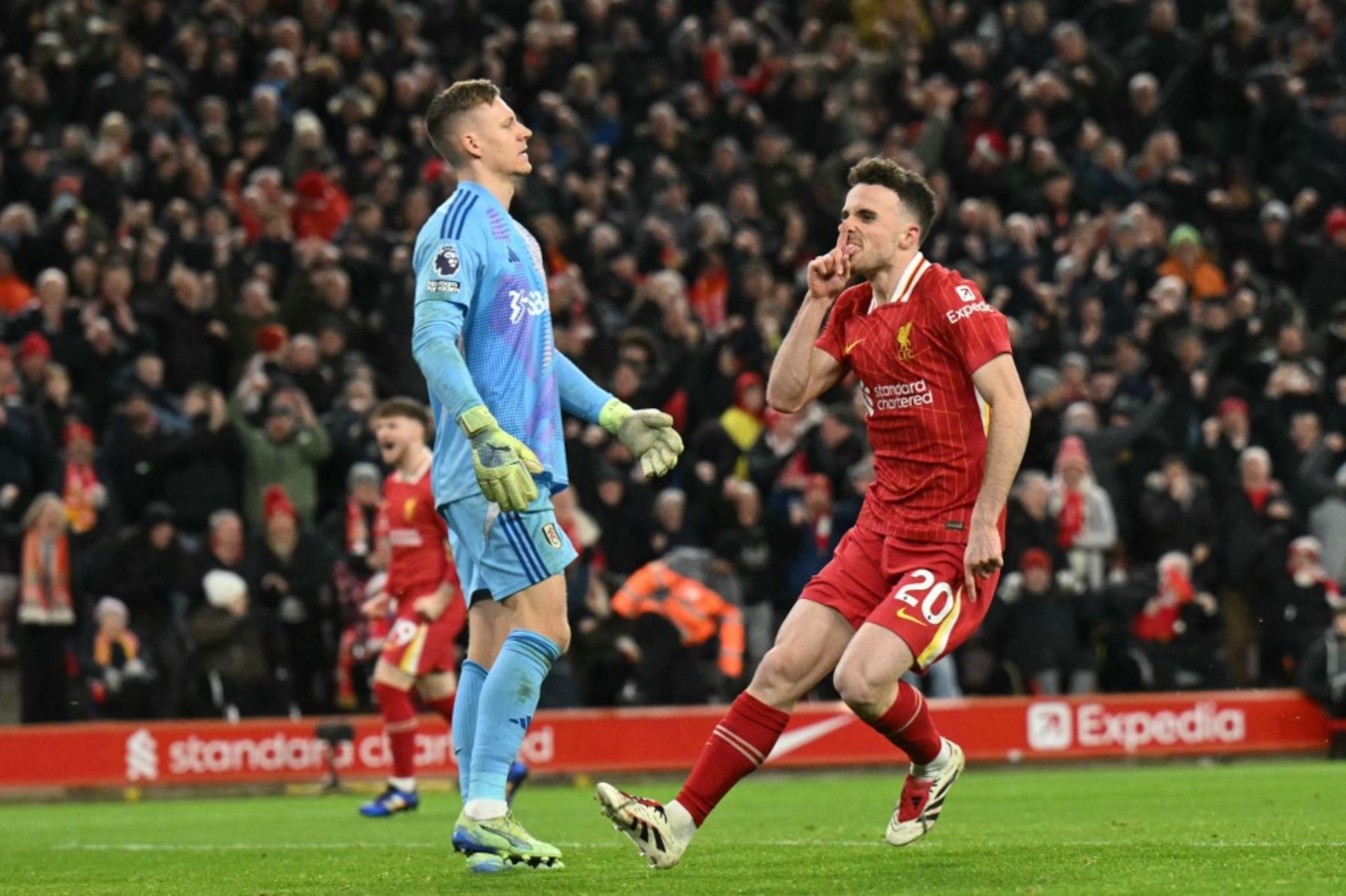 El portero alemán del Fulham #01 Bernd Leno (Izquierda) reacciona mientras el delantero portugués del Liverpool #20 Diogo Jota (R) celebra su segundo gol durante el partido de fútbol de la Premier League inglesa entre Liverpool y Fulham en Anfield en Liverpool, noroeste de Inglaterra el 14 de diciembre de 2024. (Foto de Oli SCARFF / AFP)