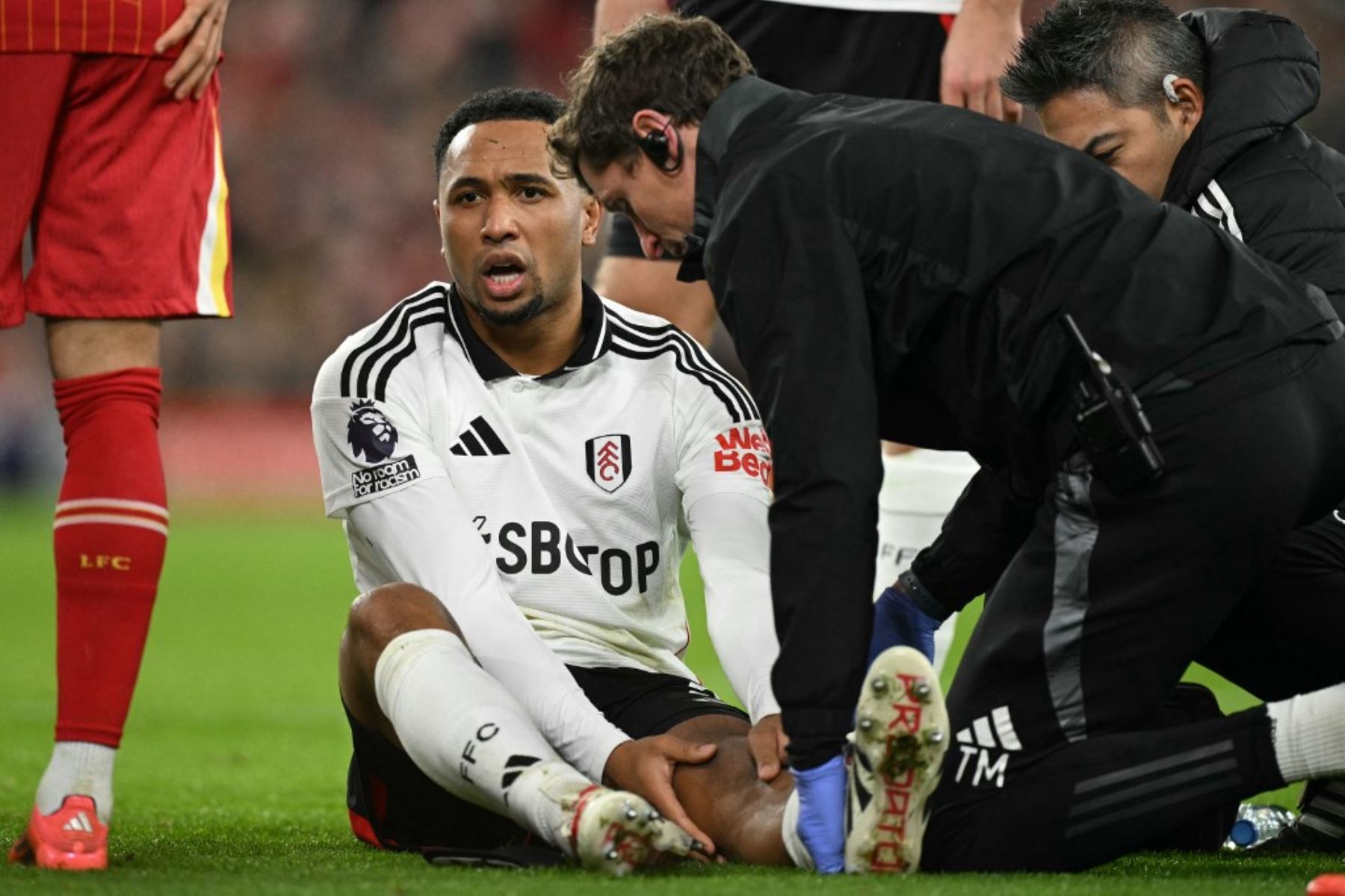 El defensor holandés del Fulham #02, Kenny Tete, es tratado por el personal médico después de sufrir una lesión durante el partido de fútbol de la Premier League inglesa entre Liverpool y Fulham en Anfield en Liverpool, noroeste de Inglaterra, el 14 de diciembre de 2024. (Foto de Oli SCARFF / AFP)