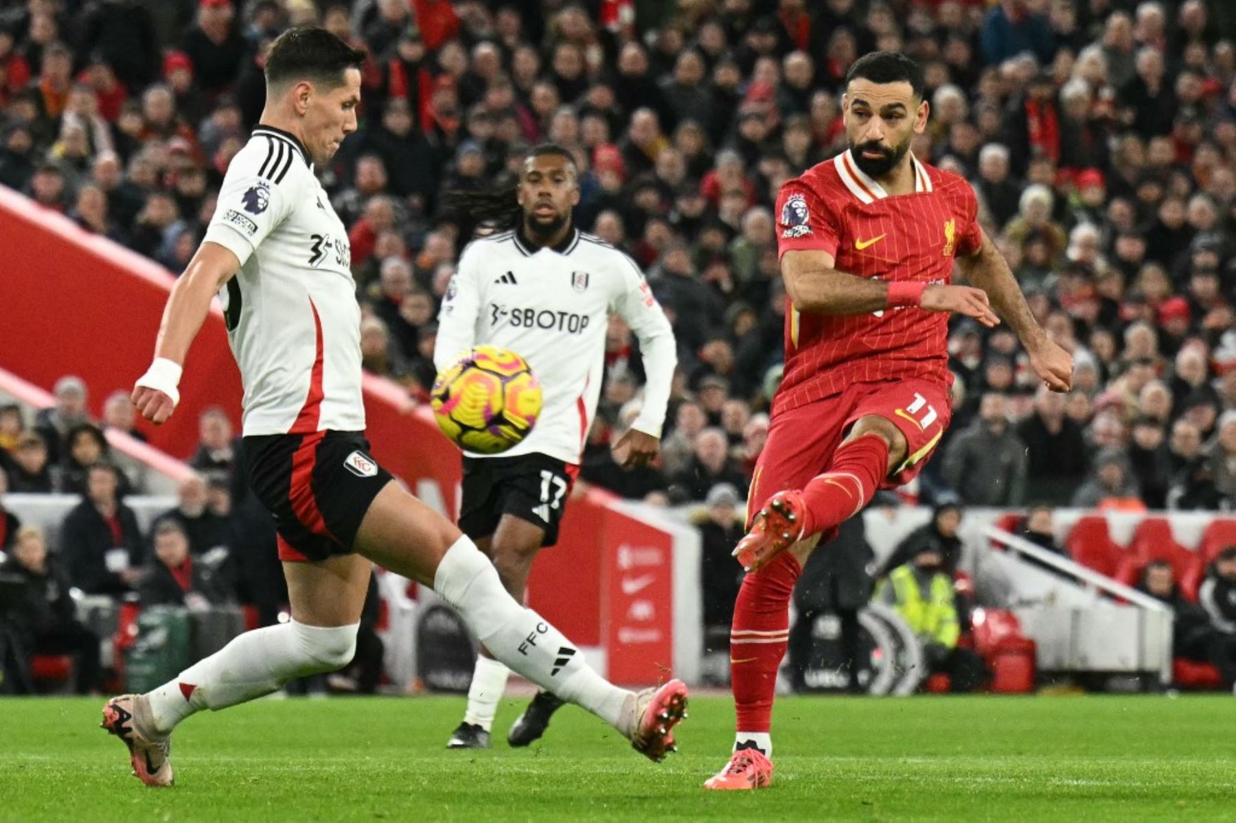 El delantero egipcio #11 del Liverpool, Mohamed Salah (R), dispara, pero no marca durante el partido de fútbol de la Premier League inglesa entre Liverpool y Fulham en Anfield, en Liverpool, noroeste de Inglaterra, el 14 de diciembre de 2024. (Foto de Oli SCARFF / AFP)