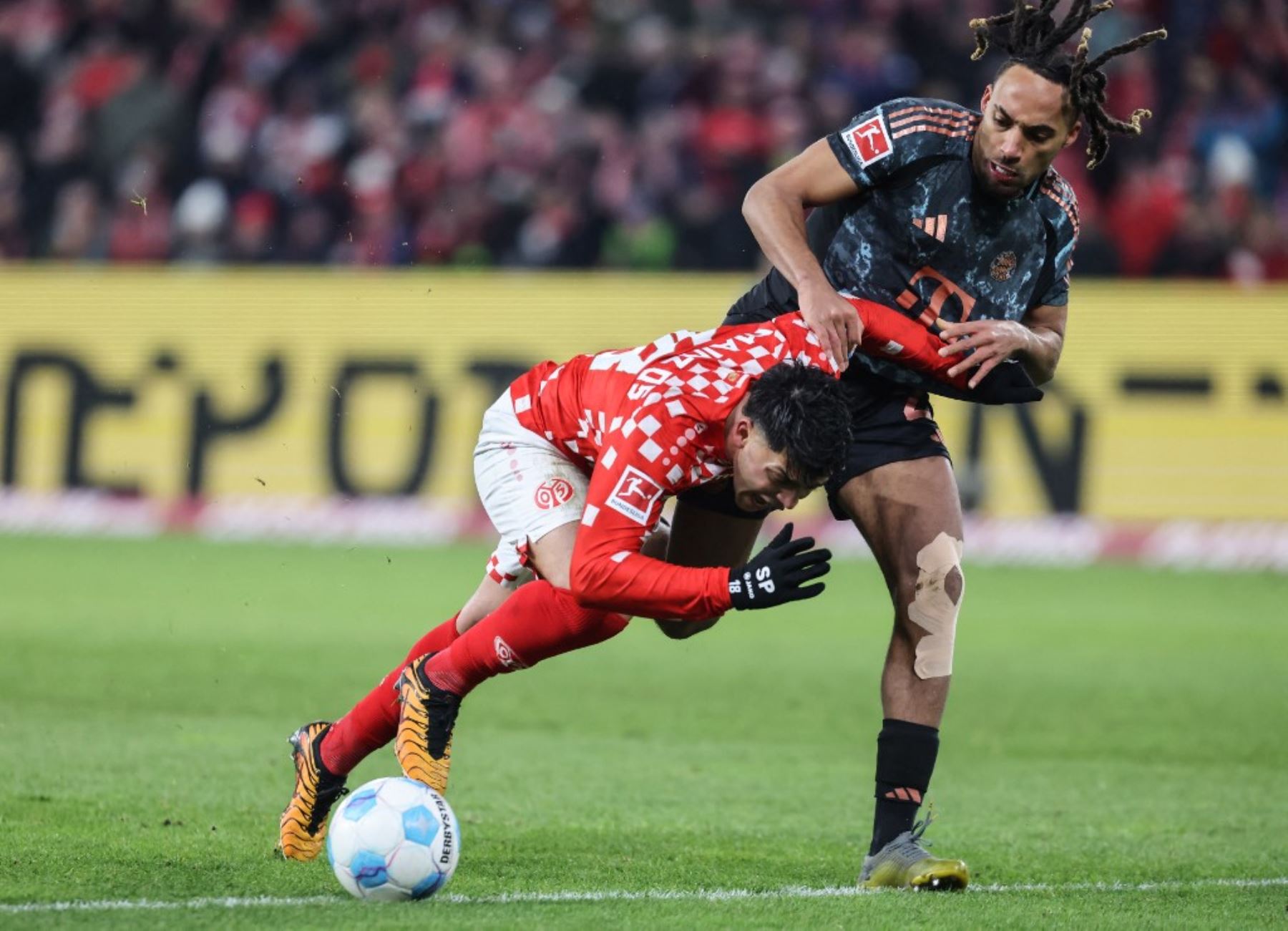 El centrocampista alemán de Augsburgo #18 Tim Breithaupt (L) y el defensor francés #23 del Bayern Munich, Sacha Boey compiten por el balón durante el partido de fútbol de la Bundesliga de primera división alemana entre 1 FSV Mainz 05 y FC Bayern Munich en Mainz, oeste de Alemania, el 14 de diciembre de 2024. (Foto de Daniel ROLAND / AFP)