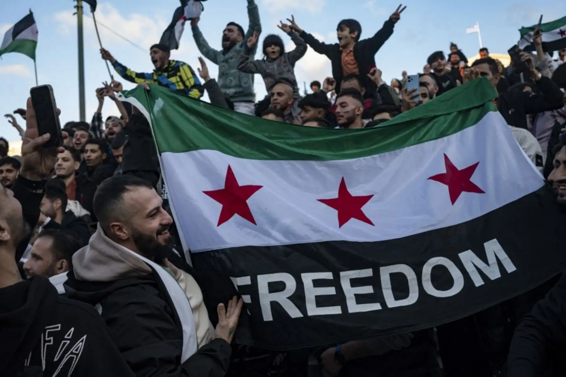 Un manifestante sostiene una bandera de la oposición siria mientras los miembros de la comunidad siria corean consignas en la plaza Syntagma de Atenas para celebrar el fin del régimen del dictador sirio Bashar al-Assad después de que los combatientes rebeldes tomaran el control de la capital siria Damasco durante la noche, el 8 de diciembre de 2024. Los rebeldes liderados por los islamistas derrocaron al antiguo gobernante de Siria, Bashar al-Assad, en una ofensiva relámpago que un enviado de la ONU llamó "