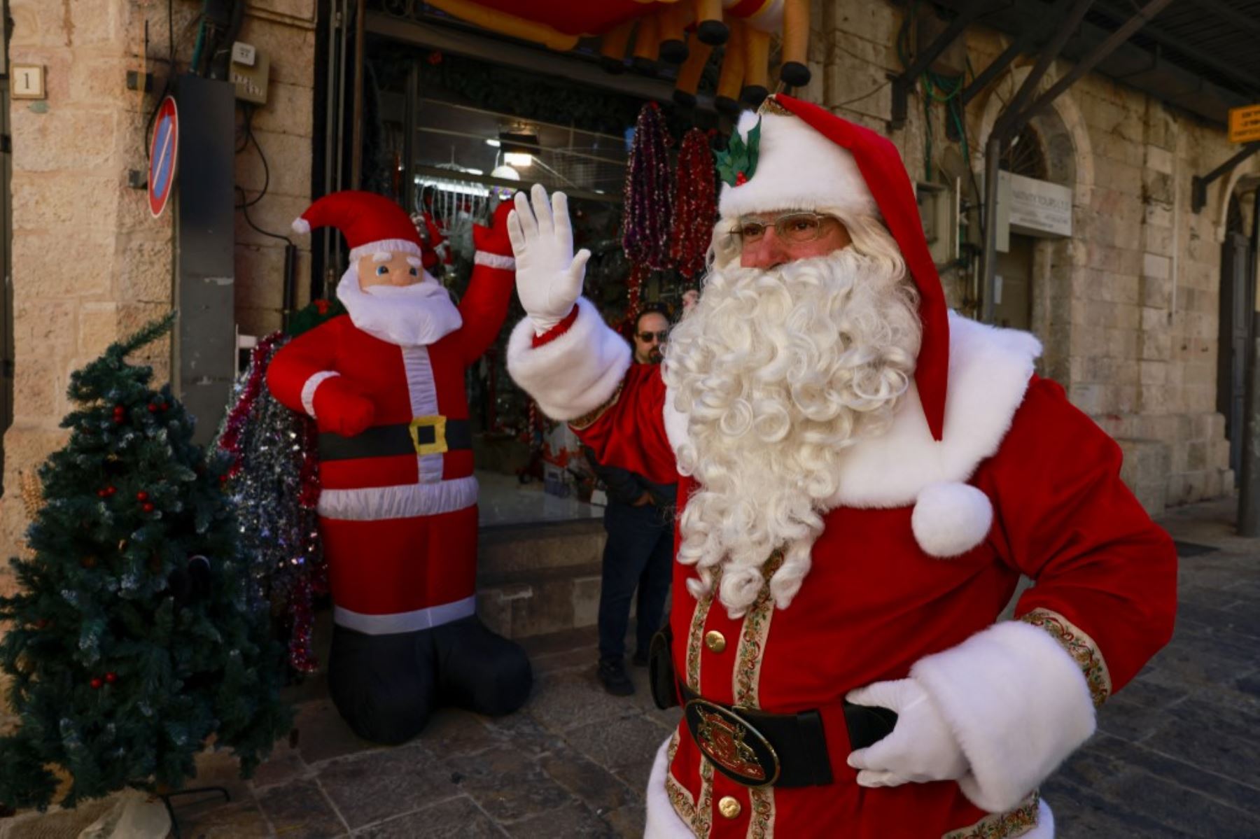 El palestino Issa Kassissieh, vestido de Papá Noel, saluda a los transeúntes en la Ciudad Vieja de Jerusalén el 19 de diciembre de 2024, antes de las próximas celebraciones por Navidad. Foto: AFP