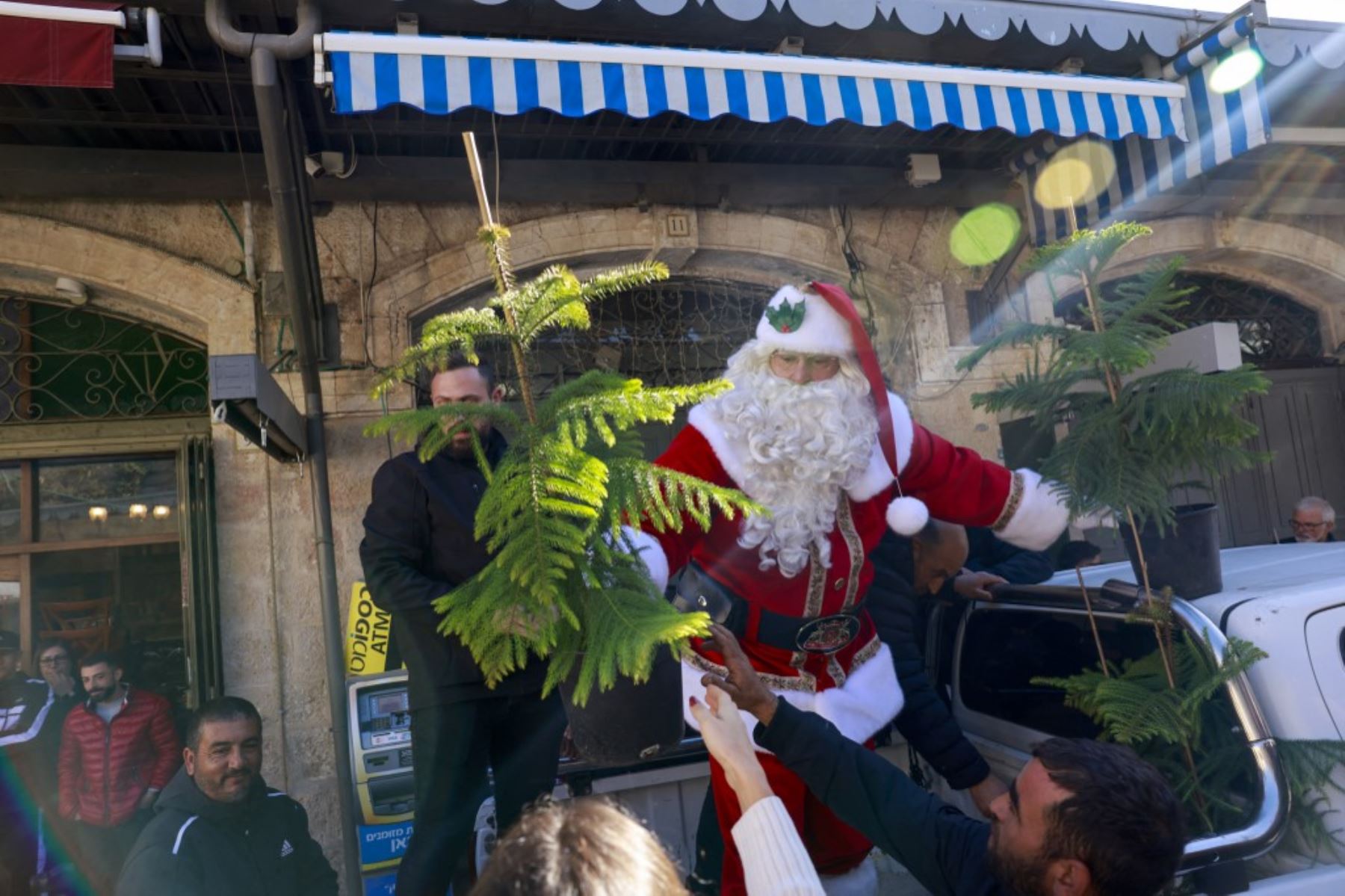 El palestino Issa Kassissieh, vestido de Papá Noel, reparte árboles de Navidad en la Ciudad Vieja de Jerusalén el 19 de diciembre de 2024, antes de las próximas celebraciones por Navidad. Foto: AFP