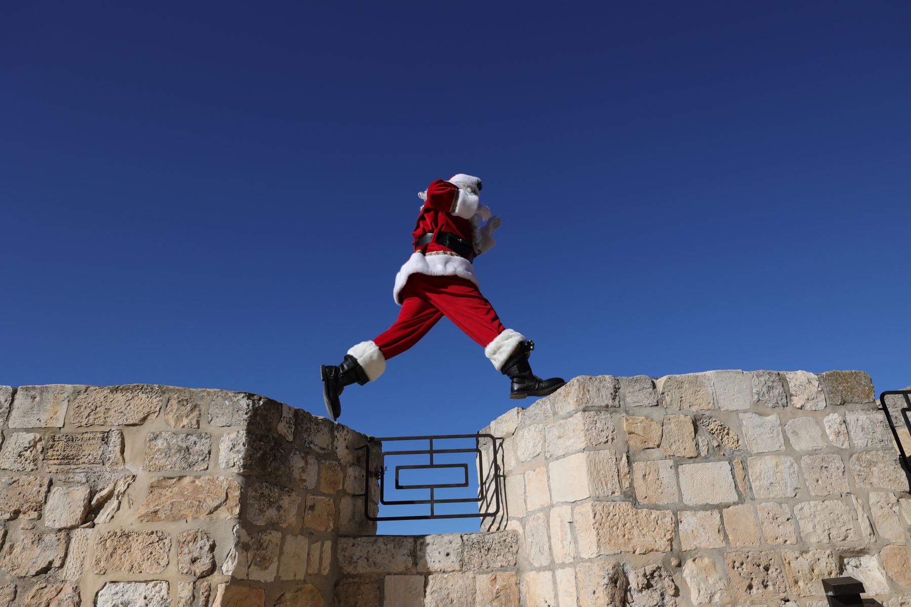 El diplomático palestino y excapitán de la selección de baloncesto palestina Issa Kassissieh salta sobre las murallas de Jerusalén, cerca de la puerta Jaffa, este jueves, para dar la bienvenida a la Navidad. Foto: EFE