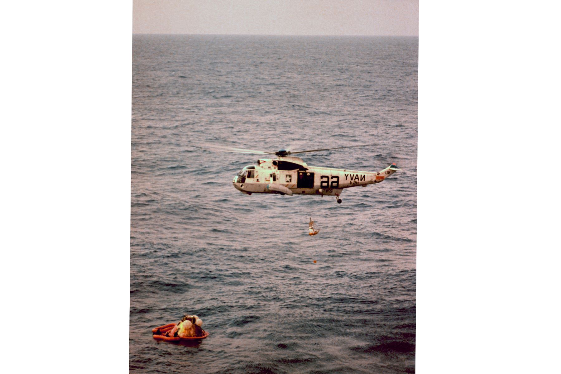 Un helicóptero de la Armada estadounidense prepara el módulo de comando del Apolo 8 para izarlo a bordo del USS Yorktown en el Pacífico, al noroeste de las islas hawaianas, el 27 de diciembre de 1968, después de su aterrizaje. La nave espacial completó un vuelo impecable con un aterrizaje preciso, a sólo tres millas de la nave de recuperación. Los astronautas del Apolo 8 fueron el comandante de la nave espacial Frank Borman, el piloto del módulo de comando James Lovell y el piloto del módulo lunar William A