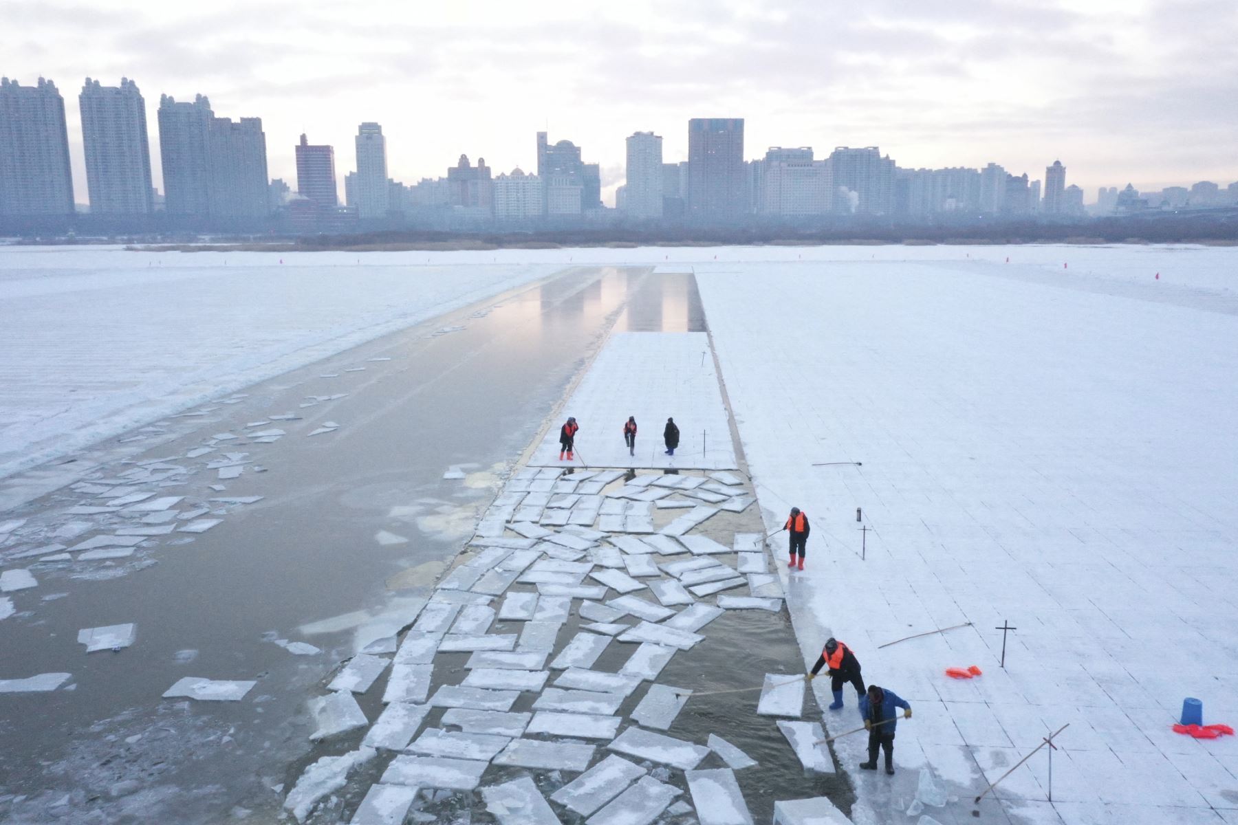 Esta imagen aérea muestra a los trabajadores cosechando hielo del río Songhua congelado en preparación para el festival anual Harbin Ice and Snow World en Harbin, al noreste de la provincia de Heilongjiang, el 17 de diciembre de 2024. (Foto de Adek BERRY / AFP)