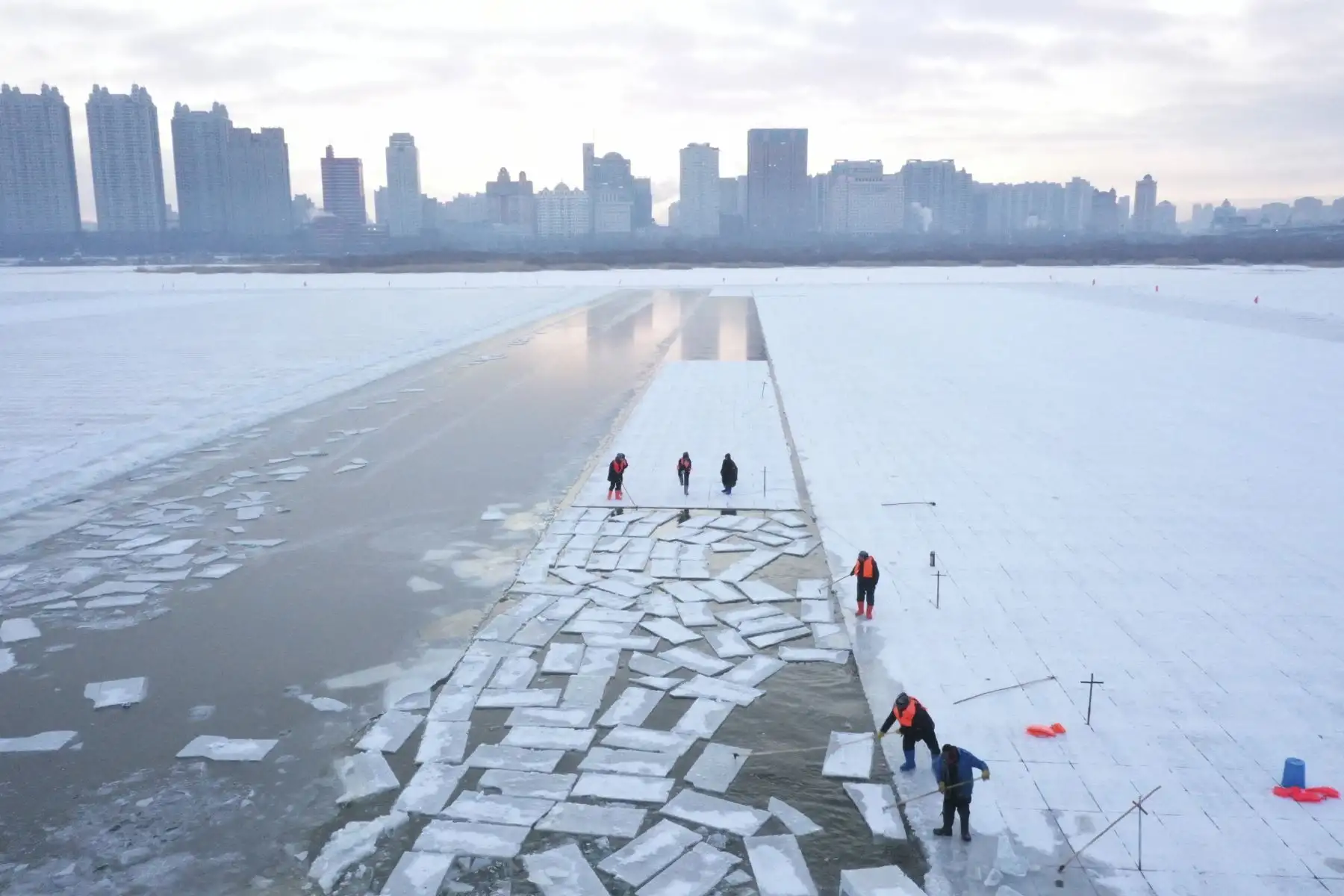 Esta imagen aérea muestra a los trabajadores cosechando hielo del río Songhua congelado en preparación para el festival anual Harbin Ice and Snow World en Harbin, al noreste de la provincia de Heilongjiang, el 17 de diciembre de 2024. (Foto de Adek BERRY / AFP)