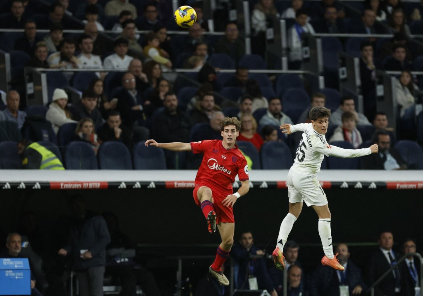 El centrocampista español del Sevilla #28 Manu Bueno y el centrocampista turco #15 del Real Madrid, Arda Guler compiten por un cabezazo durante el partido de fútbol de la liga española entre el Real Madrid CF y el Sevilla FC en el estadio Santiago Bernabéu de Madrid el 22 de diciembre de 2024. (Foto de OSCAR DEL POZO / AFP)