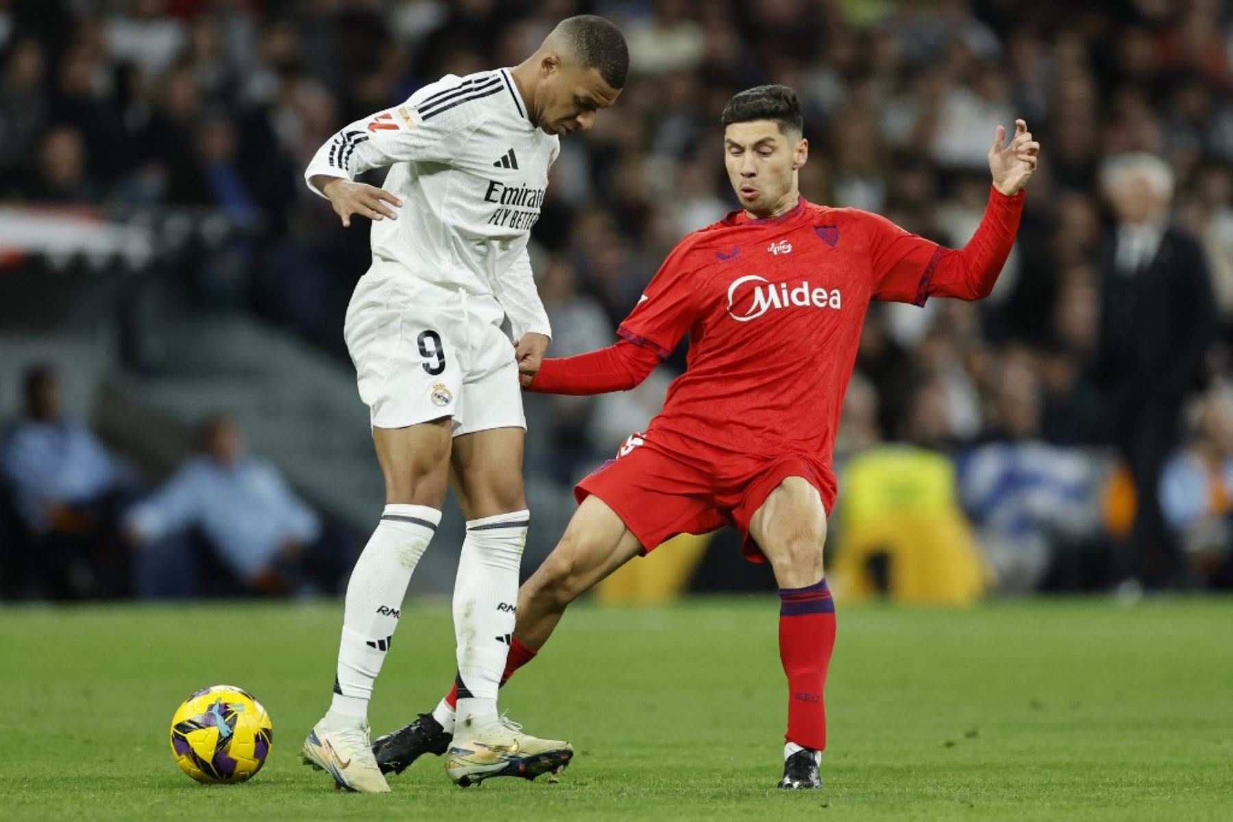 El delantero francés del Real Madrid #09 Kylian Mbappe y el defensor argentino del Sevilla #15 Gonzalo Montiel compiten por el balón durante el partido de fútbol de la liga española entre el Real Madrid CF y el Sevilla FC en el estadio Santiago Bernabéu de Madrid el 22 de diciembre de 2024. (Foto de OSCAR DEL POZO / AFP)