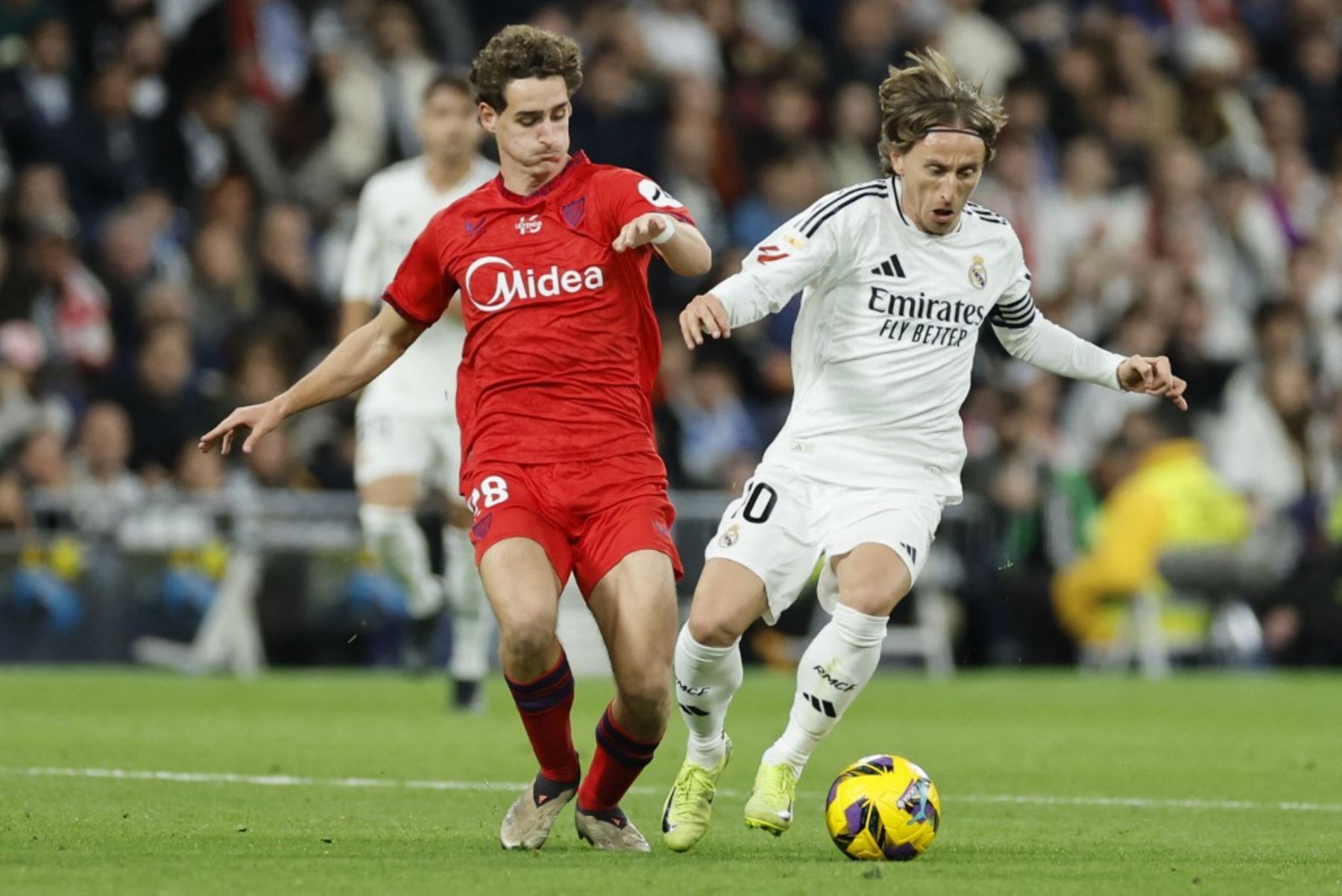 El centrocampista español del Sevilla #28 Manu Bueno y el centrocampista croata #10 del Real Madrid Luka Modric compiten por el balón durante el partido de fútbol de la liga española entre el Real Madrid CF y el Sevilla FC en el estadio Santiago Bernabeu de Madrid el 22 de diciembre de 2024. (Foto de OSCAR DEL POZO / AFP)