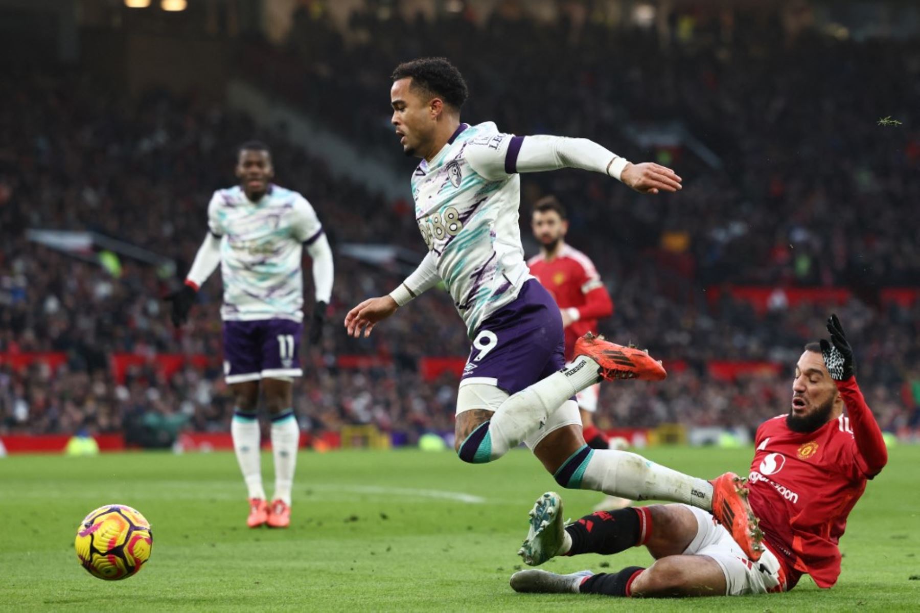 El defensor marroquí del Manchester United #03 Noussair Mazraoui (R) comete una falta al delantero holandés del Bournemouth #19 Justin Kluivert (C) por un penalti durante el partido de fútbol de la Premier League inglesa entre el Manchester United y el Bournemouth en Old Trafford en Manchester, noroeste de Inglaterra, el 22 de diciembre de 2024. (Foto de Darren Staples / AFP)