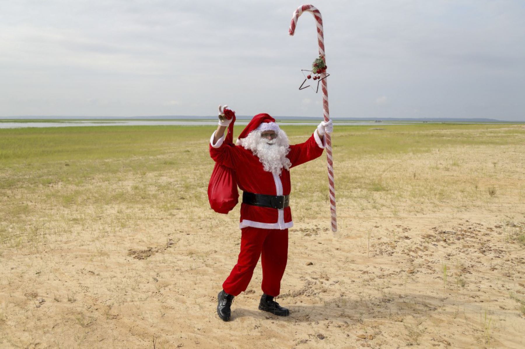 El voluntario Jorge Alberto Barroso, vestido de Papá Noel, camina por una playa en el Río Negro para entregar regalos a los niños de la comunidad ribereña de Abelha, en la ciudad de Manaos, estado de Amazonas, norte de Brasil, el 20 de diciembre de 2024. Desde 1998, el grupo "Amigos de Papá Noel" ha estado promoviendo la Navidad para los niños en las comunidades rurales y ribereñas de la selva amazónica. (Foto de MICHAEL DANTAS / AFP)