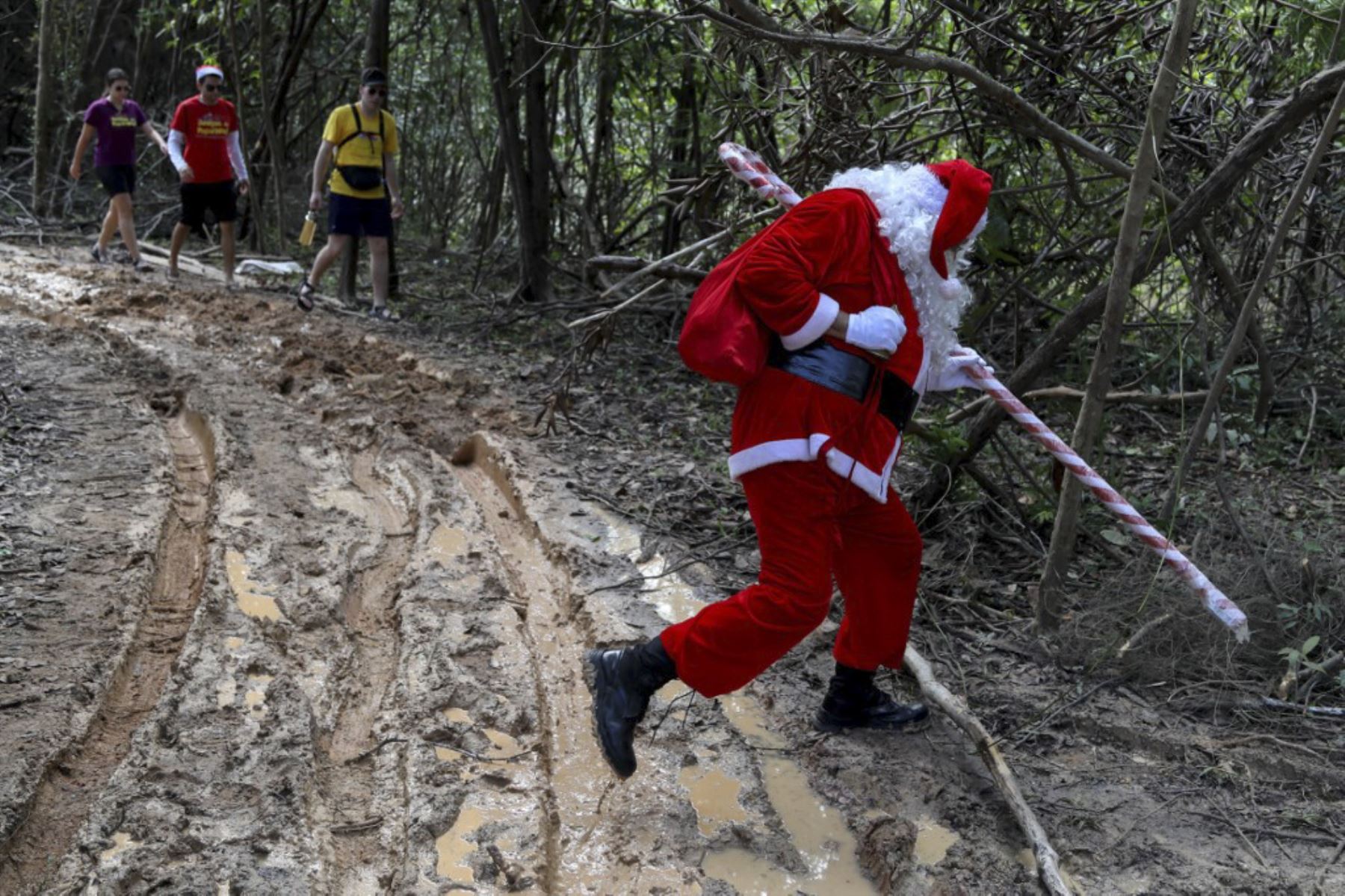 El voluntario Jorge Alberto Barroso, vestido de Papá Noel, va por una carretera fangosa para entregar regalos a los niños en la comunidad ribereña de Abelha, en la ciudad de Manaos, estado de Amazonas, norte de Brasil, el 20 de diciembre de 2024. Desde 1998, el grupo "Amigos de Papá Noel" ha estado promoviendo la Navidad para los niños en las comunidades rurales y ribereñas de la selva amazónica. (Foto de MICHAEL DANTAS / AFP)