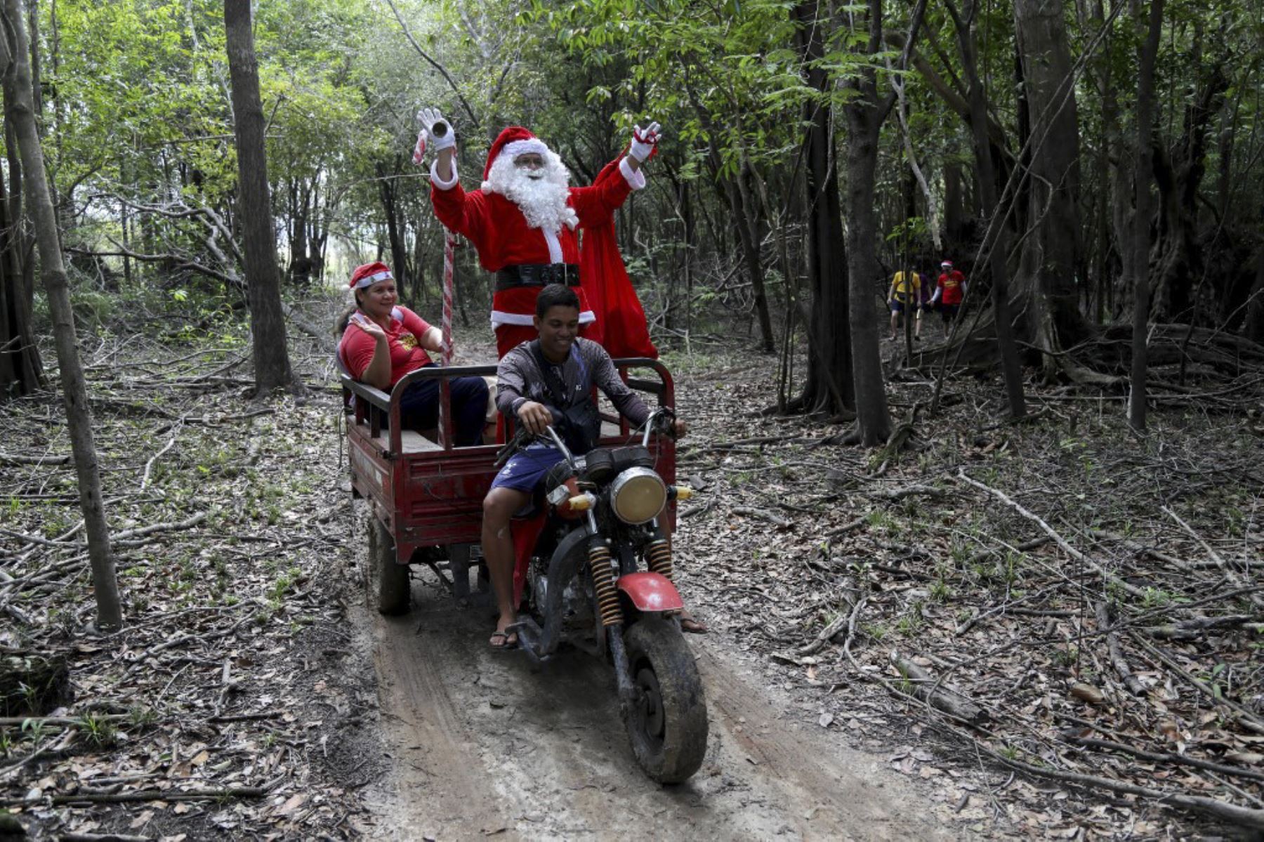 El voluntario Jorge Alberto Barroso, vestido de Papá Noel, es transportado en triciclo para entregar regalos a los niños en la comunidad ribereña de Abelha, en la ciudad de Manaus, estado de Amazonas, norte de Brasil, el 20 de diciembre de 2024. Desde 1998, el grupo "Amigos de Papá Noel" ha estado promoviendo la Navidad para los niños en las comunidades rurales y ribereñas de la selva amazónica. (Foto de MICHAEL DANTAS / AFP)