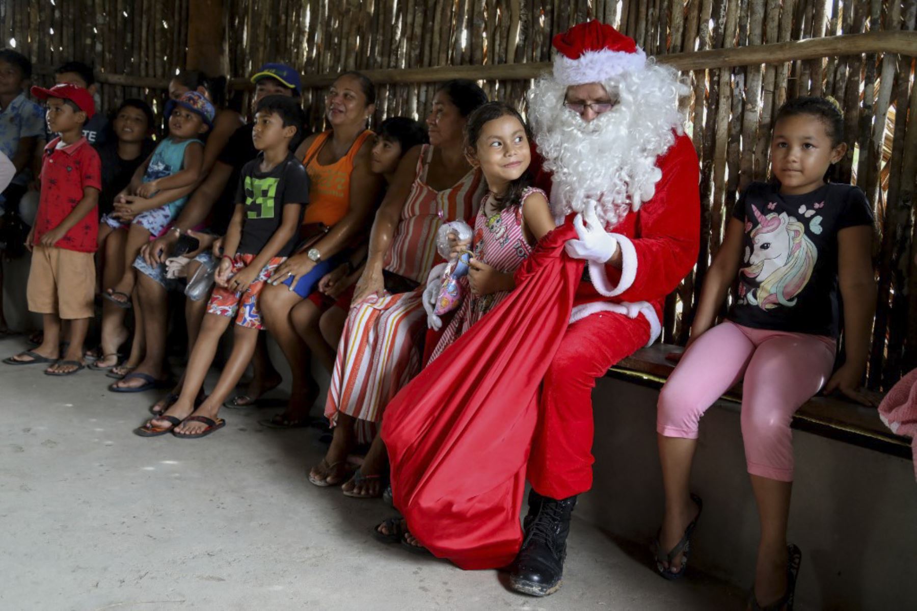 El voluntario Jorge Alberto Barroso, vestido de Papá Noel, entrega regalos a los niños en la comunidad ribereña de Abelha, en la ciudad de Manaus, estado de Amazonas, norte de Brasil, el 20 de diciembre de 2024. Desde 1998, el grupo "Amigos de Papá Noel" ha estado promoviendo la Navidad para los niños en las comunidades rurales y ribereñas de la selva amazónica. (Foto de MICHAEL DANTAS / AFP)