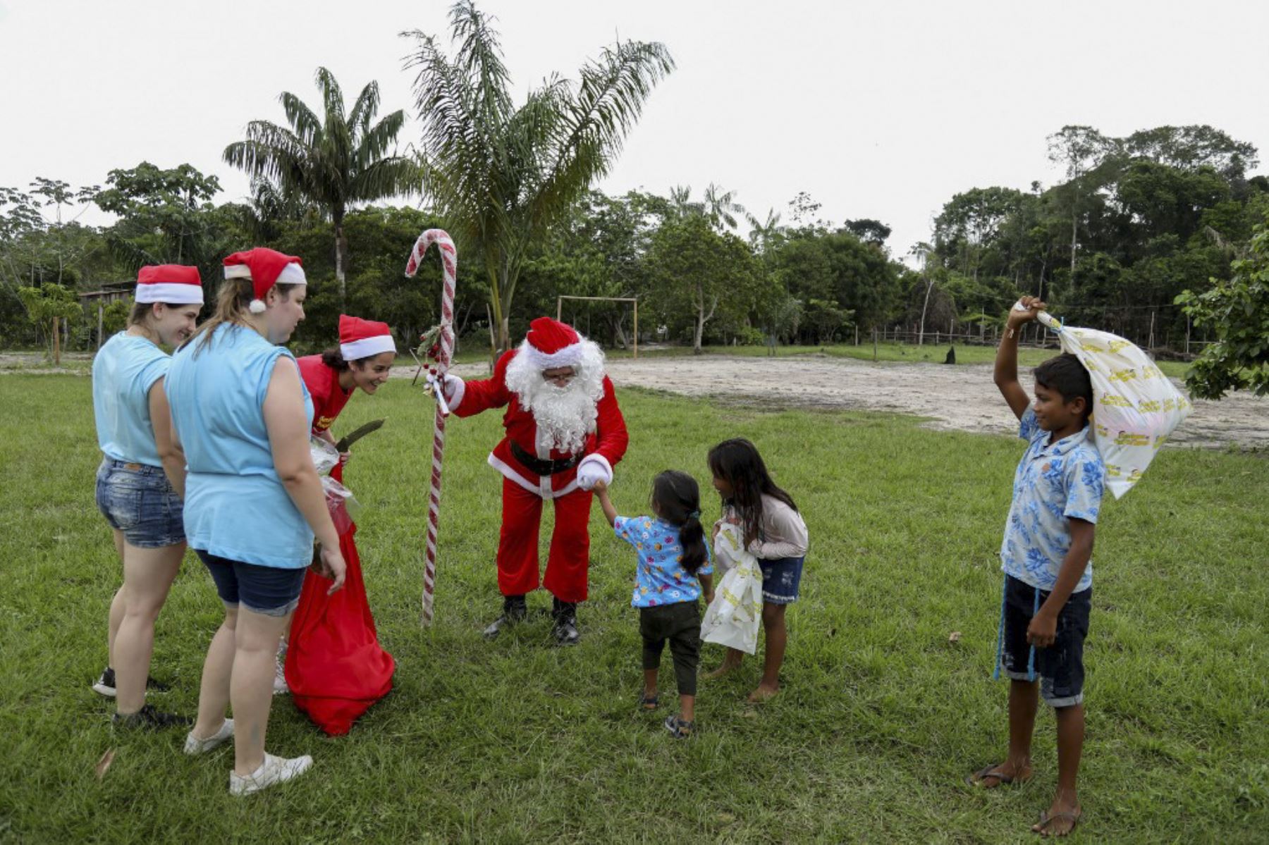 El voluntario Jorge Alberto Barroso, vestido de Papá Noel, es recibido por niños al llegar para entregar regalos en la comunidad ribereña de Abelha, en la ciudad de Manaos, estado de Amazonas, norte de Brasil, el 20 de diciembre de 2024. Desde 1998, el grupo "Amigos de Papá Noel" ha estado promoviendo la Navidad para los niños en las comunidades rurales y ribereñas de la selva amazónica. (Foto de MICHAEL DANTAS / AFP)