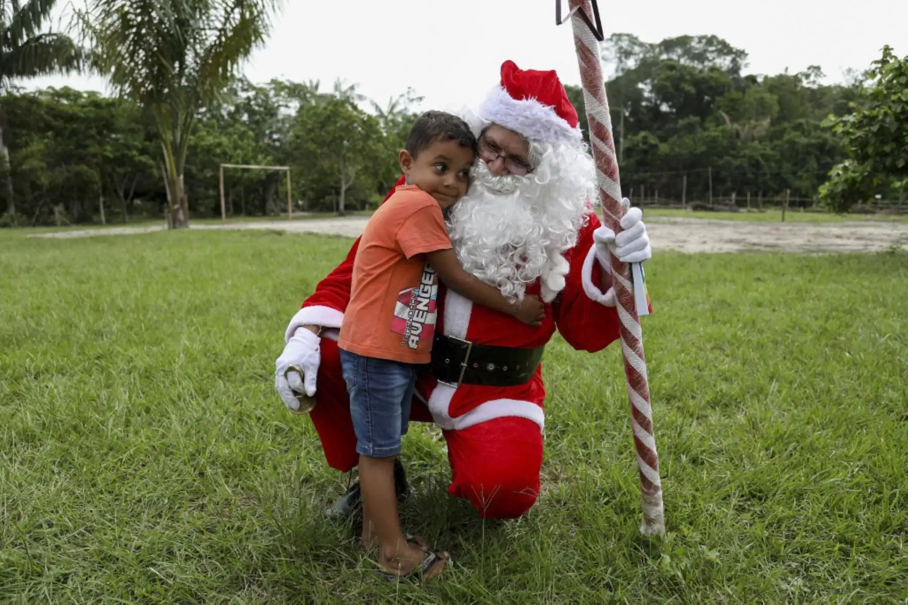El voluntario Jorge Alberto Barroso, vestido de Papá Noel, es abrazado por un niño al llegar para entregar regalos en la comunidad ribereña de Abelha, en la ciudad de Manaus, estado de Amazonas, norte de Brasil, el 20 de diciembre de 2024. Desde 1998, el grupo "Amigos de Papá Noel" ha estado promoviendo la Navidad para los niños en las comunidades rurales y ribereñas de la selva amazónica. (Foto de MICHAEL DANTAS / AFP)