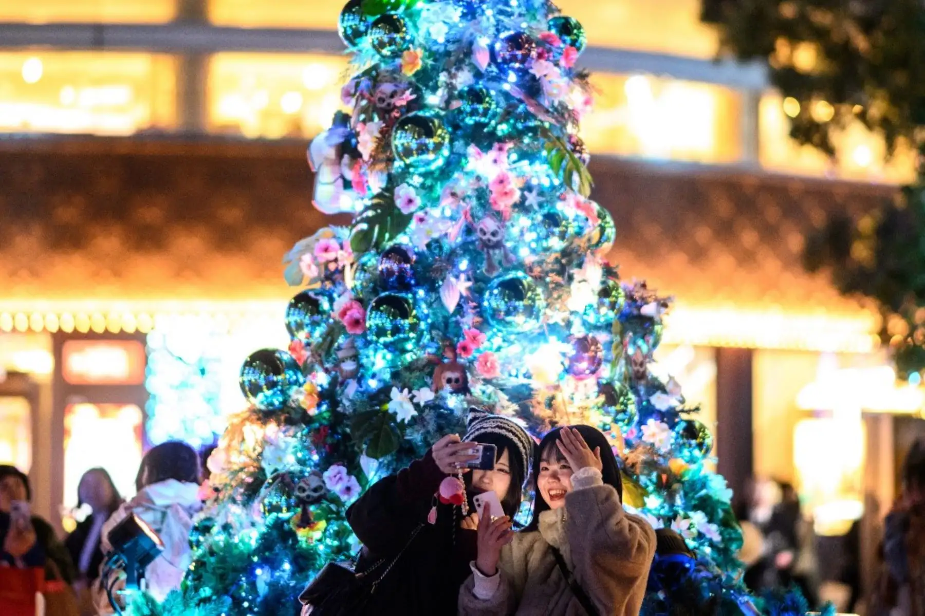 El mundo, con todas sus conflictos, diferencias y problemas, se une en una celebración que se ha vuelto costumbre, independientemente de sus religiones: La Navidad. Aquí en la imagen se puede apreciar a una pareja que se toma un selfie frente a un árbol de Navidad en el barrio de Hibiya de Tokio. Foto: AFP