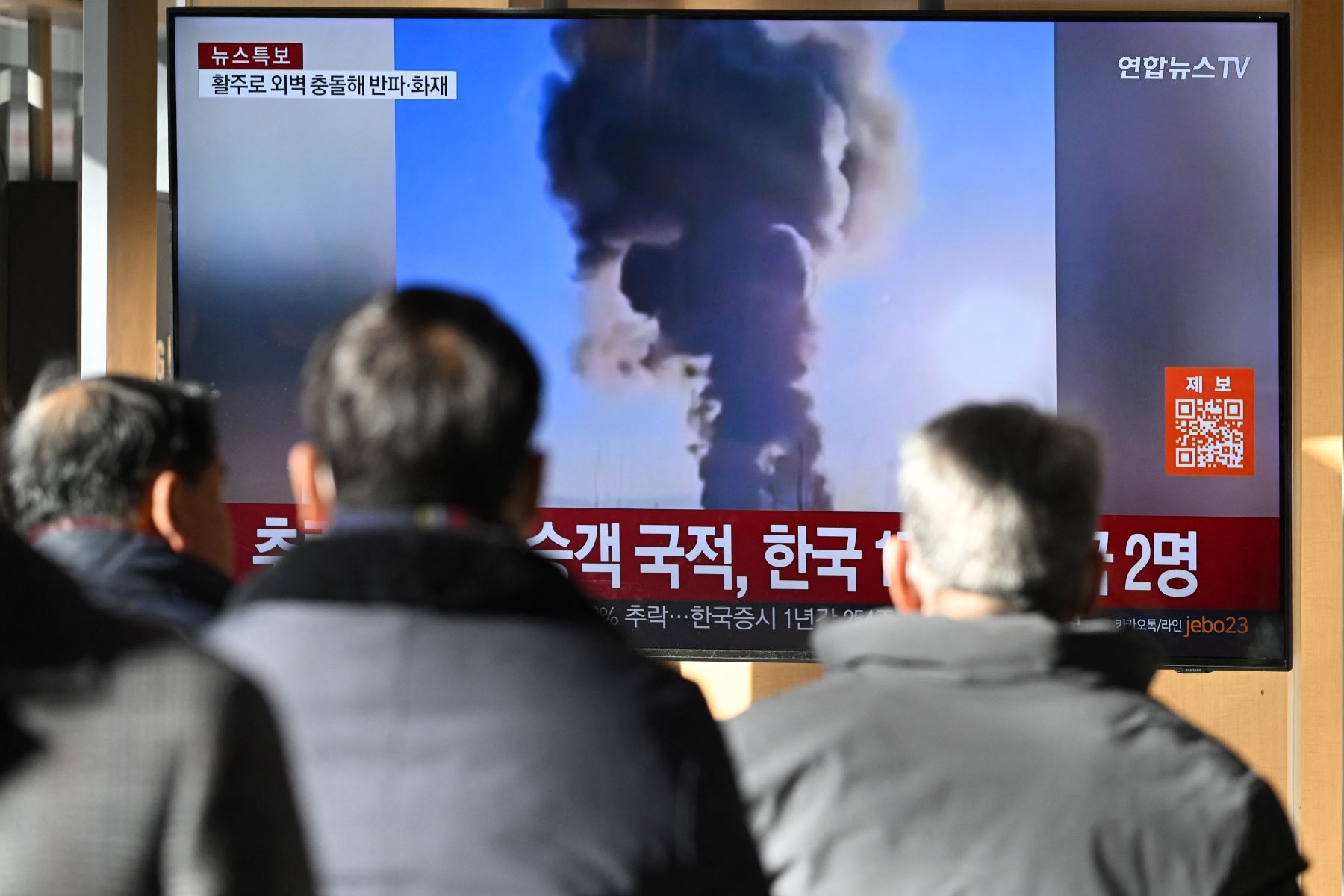 Las personas  ven una pantalla de televisión que transmite imágenes de un accidente aéreo en el aeropuerto internacional de Muan, en una estación de tren de Seúl, 
Foto: AFP