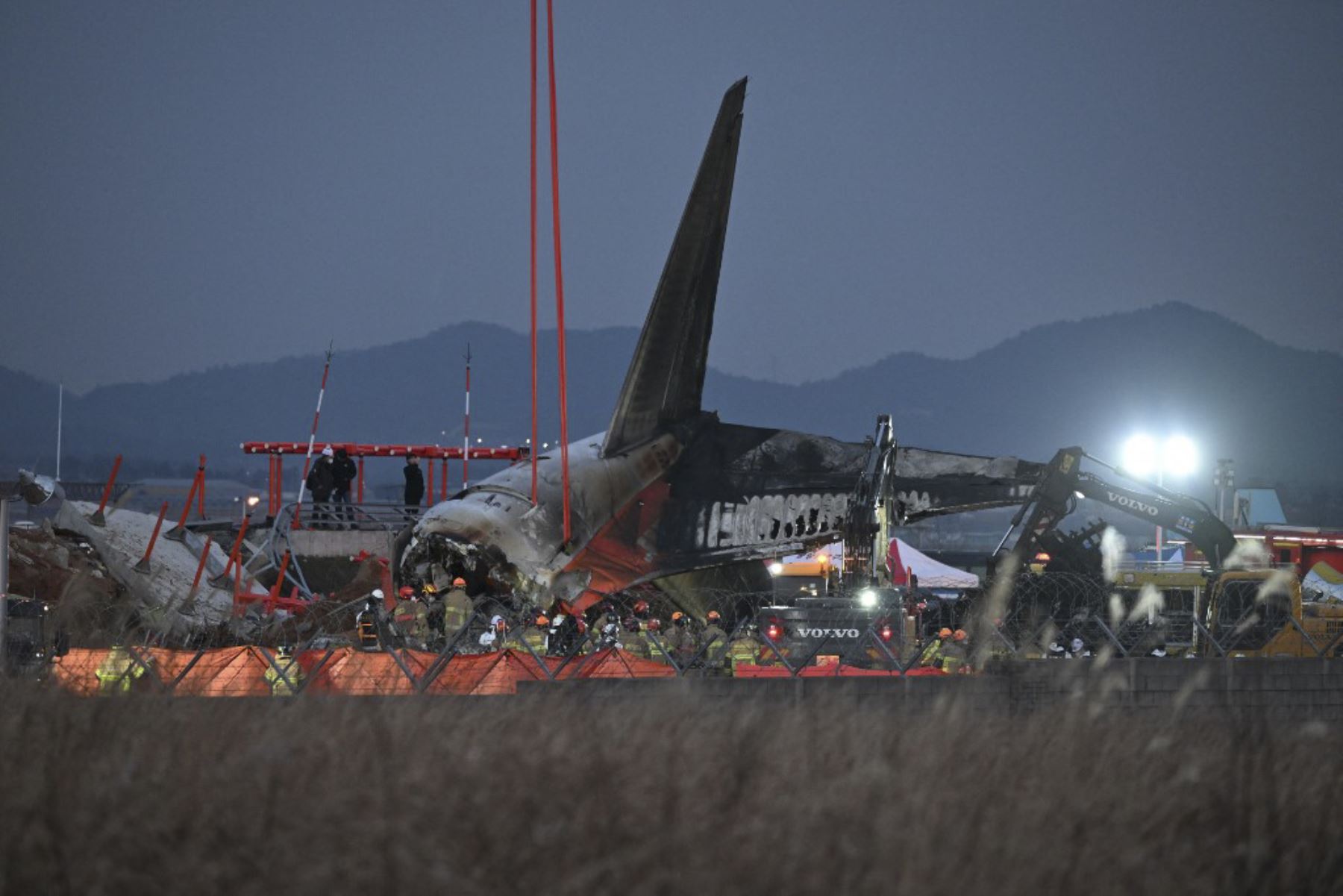 Los bomberos y el personal de rescate trabajan cerca de la escena donde un avión de la serie Boeing 737-800 de Jeju Air se estrelló y se incendió en el Aeropuerto Internacional de Muan, en la provincia de South Jeolla, a unos 288 kilómetros al suroeste de Seúl, el 29 de diciembre de 2024. Un avión de Jeju Air que transportaba a 181 personas de Tailandia a Corea del Sur se estrelló al llegar, estrellando contra una barrera y estallando en llamas, dejando a todos menos a dos temidos muertos. (Foto de JUNG YEO