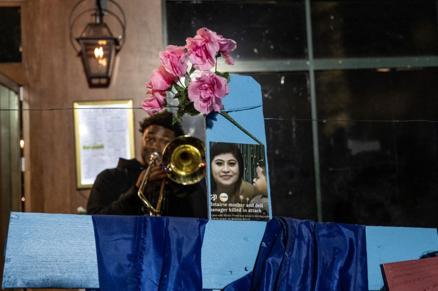 Un miembro de una banda toca junto a una cruz con una foto de la víctima Nicole Pérez, de 27 años, en un monumento conmemorativo en Bourbon Street después de que reabriera al público, en Nueva Orleans, Luisiana. Foto: AFP