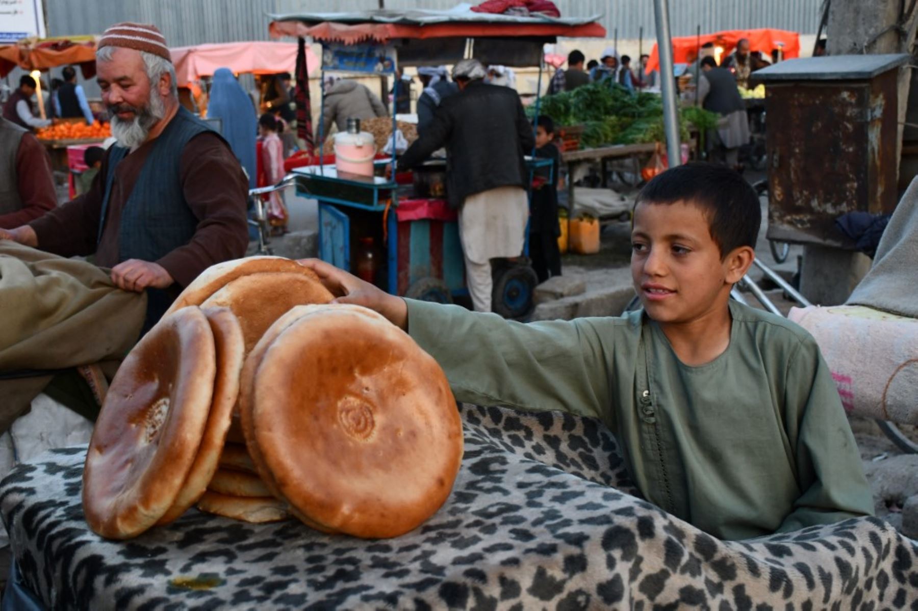 Un niño afgano que vende pan espera a los clientes en un puesto de carretera en Mazar-i-Sharif. (Foto de Atif Aryan / AFP)