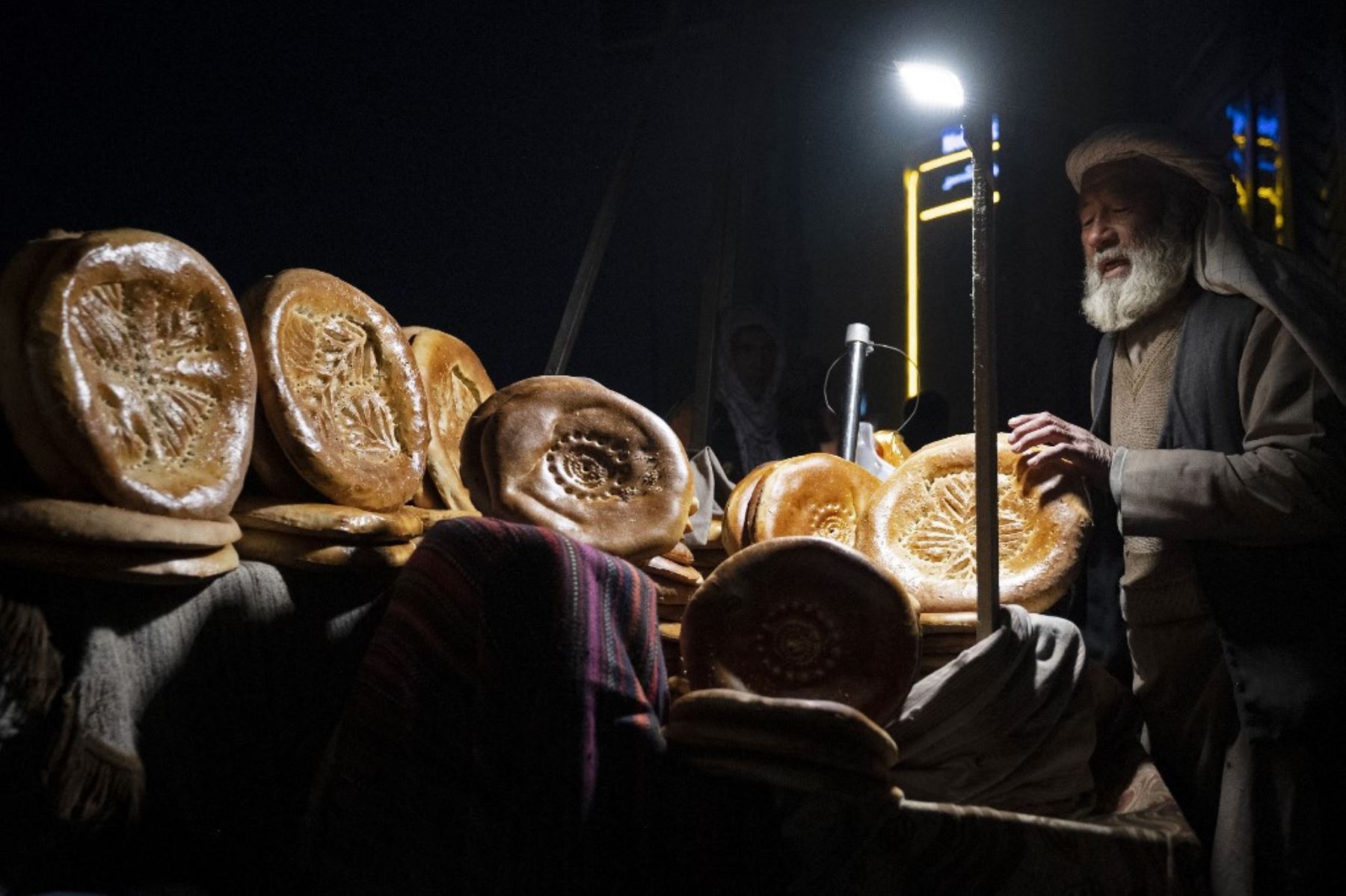 Esta fotografía muestra a un vendedor afgano vendiendo panes planos tradicionales conocidos localmente como Naan, en un mercado de carretera en Kabul. Para muchos en Afganistán, uno de los países más pobres del mundo, donde 12,4 millones de personas viven en inseguridad alimentaria aguda, según el Programa Mundial de Alimentos, el pan constituye la mayor parte de las comidas. El pan afgano es uno de los pocos alimentos que todo el mundo puede permitirse, con precios tan bajos como 10 afganos (0,14) centavos. Foto: AFP